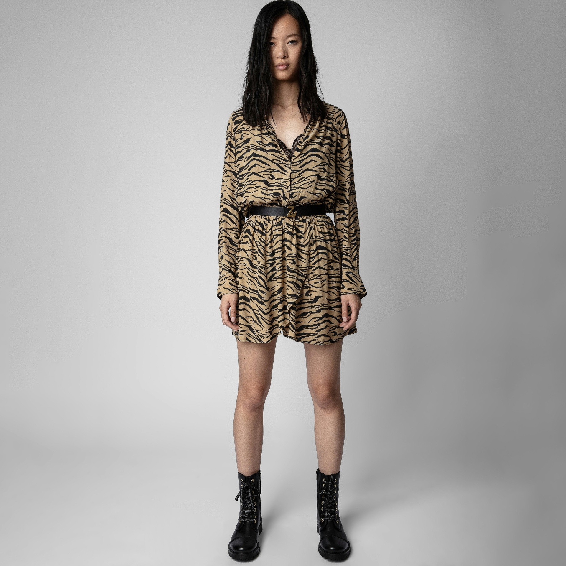 Vestido curto animal print com cinto preto e botas pretas.