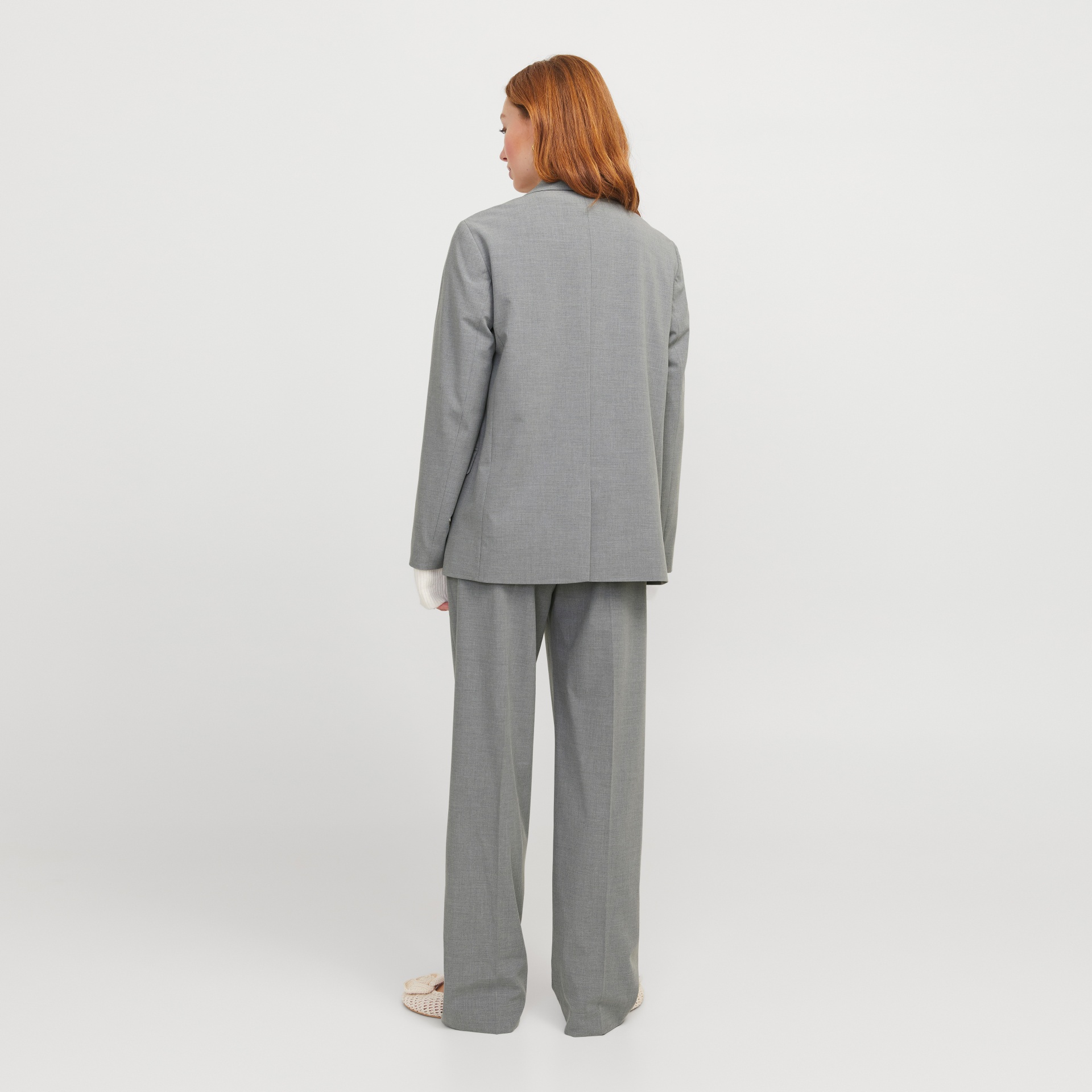 Mulher vista de costas a usar terno cinzento liso com casaco e calças