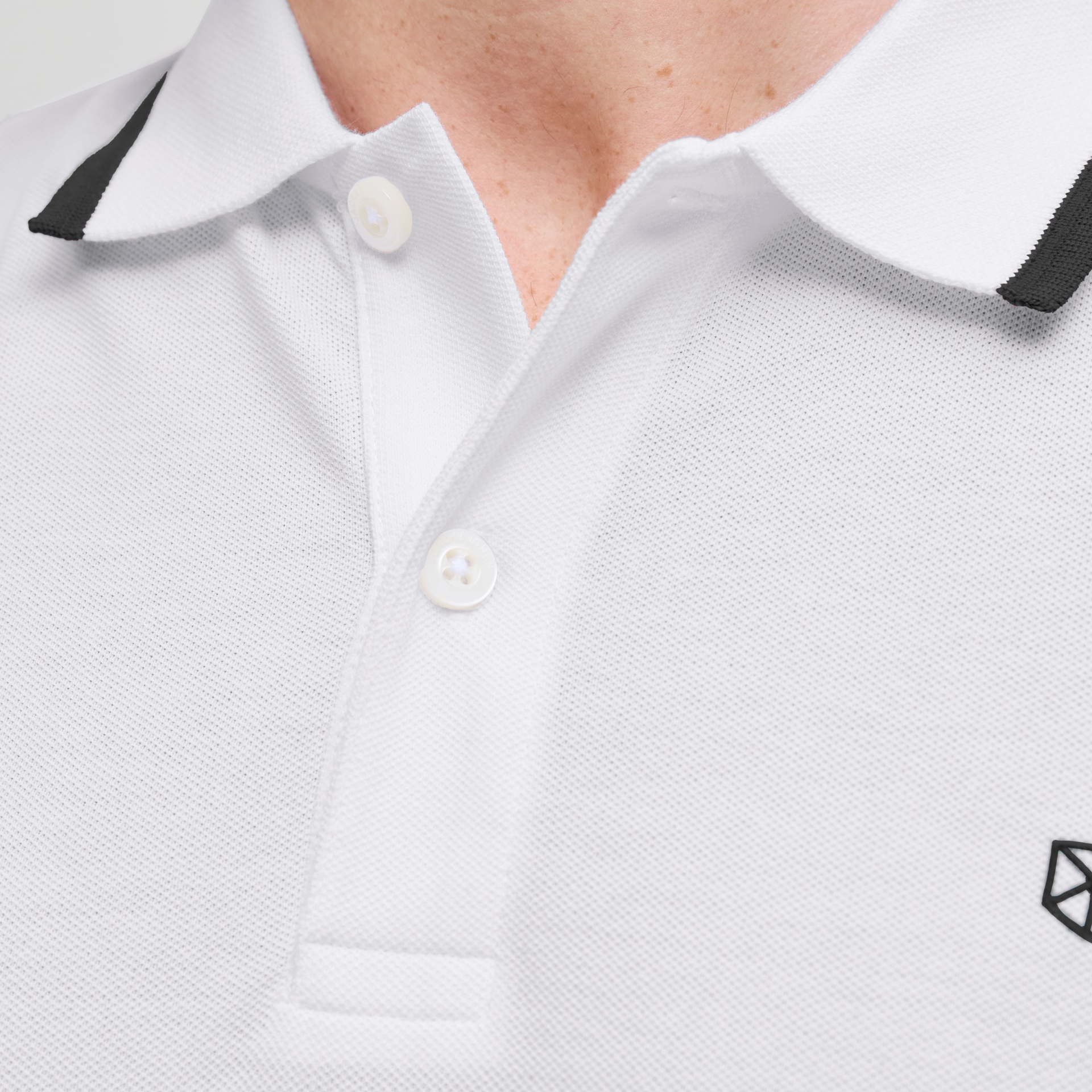 Polo branco com gola preta e pequeno logotipo preto no peito
