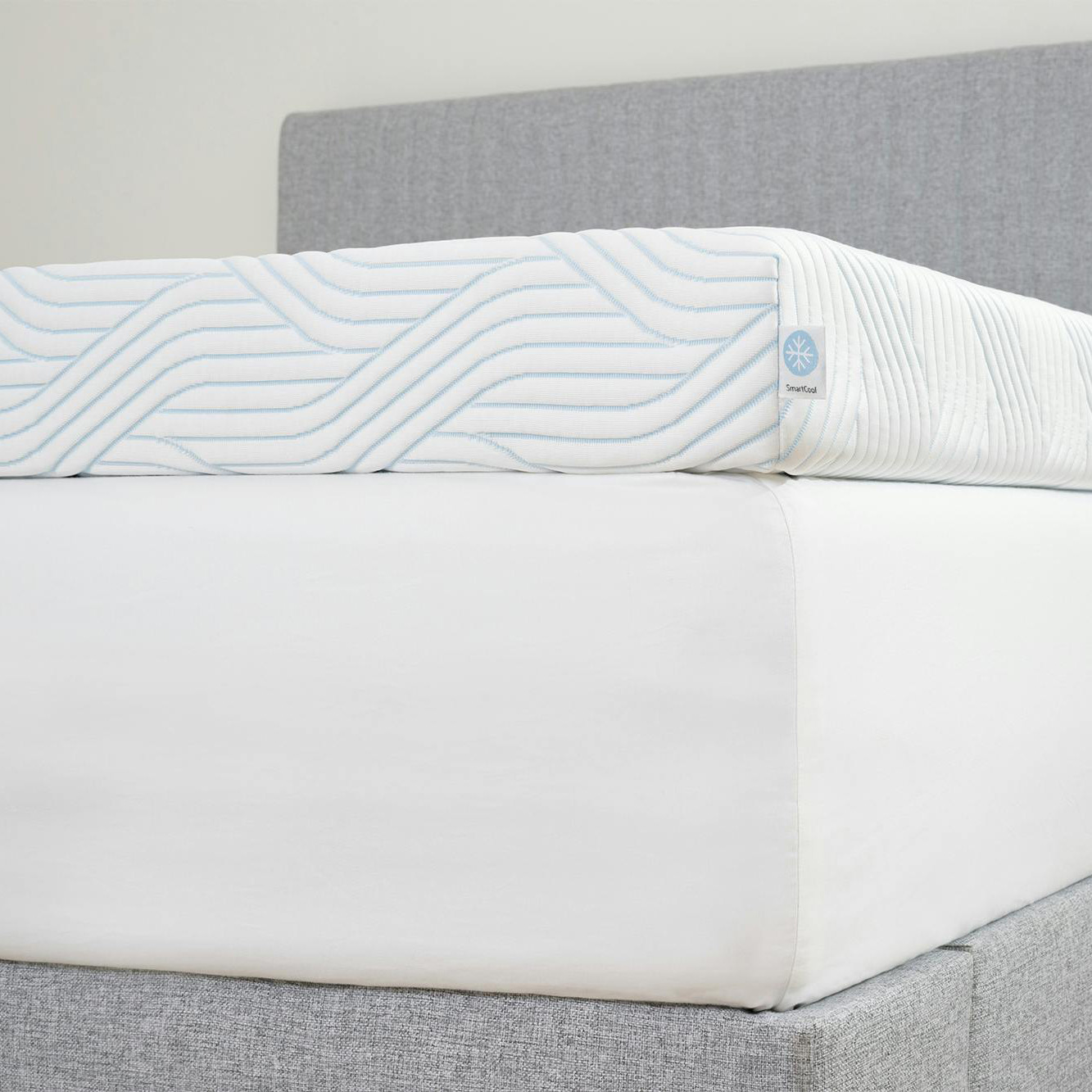 Colchão branco com padrão azul e etiqueta SmartCool em cama cinza