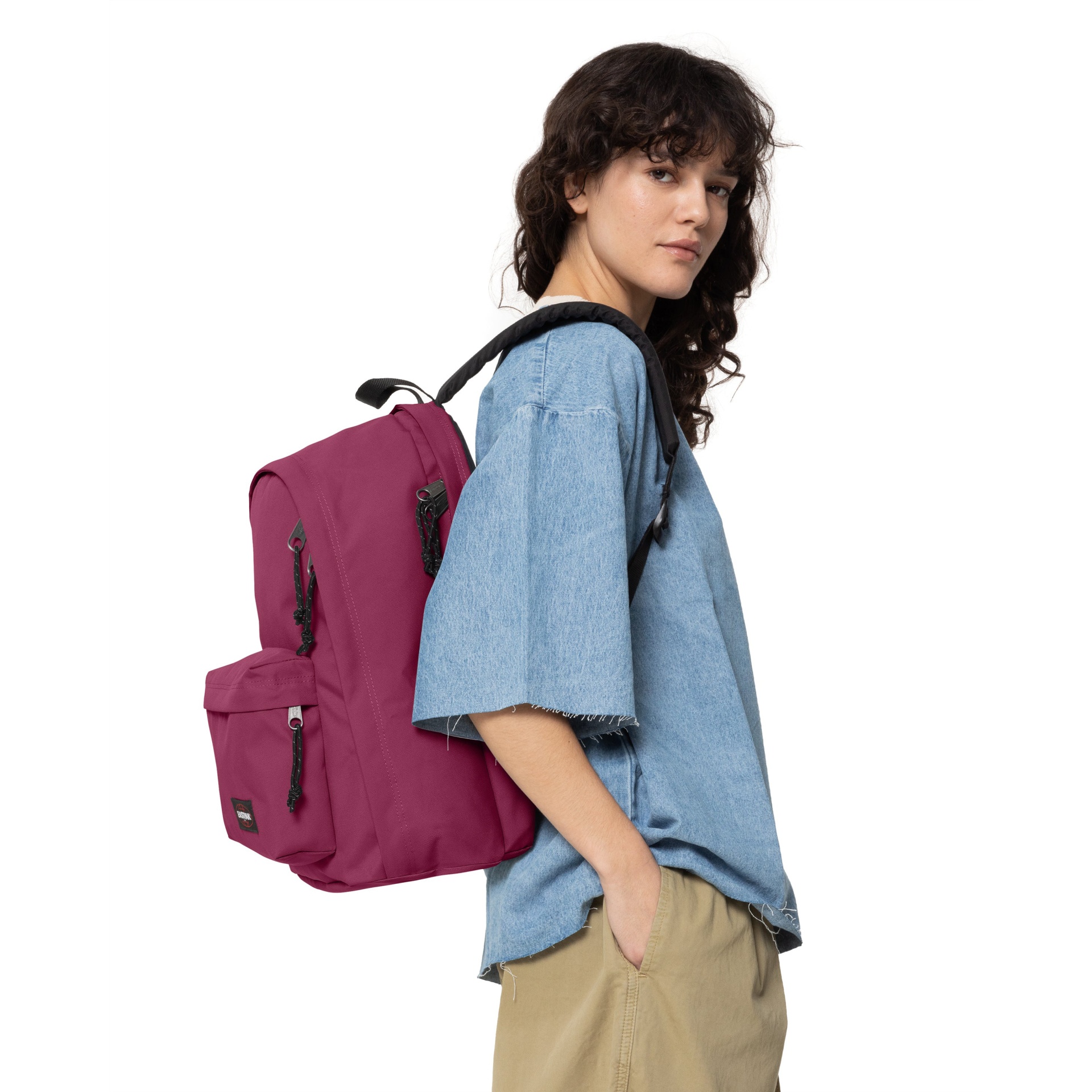 Mochila rosa em tecido usada por pessoa com camisa azul clara e calças bege