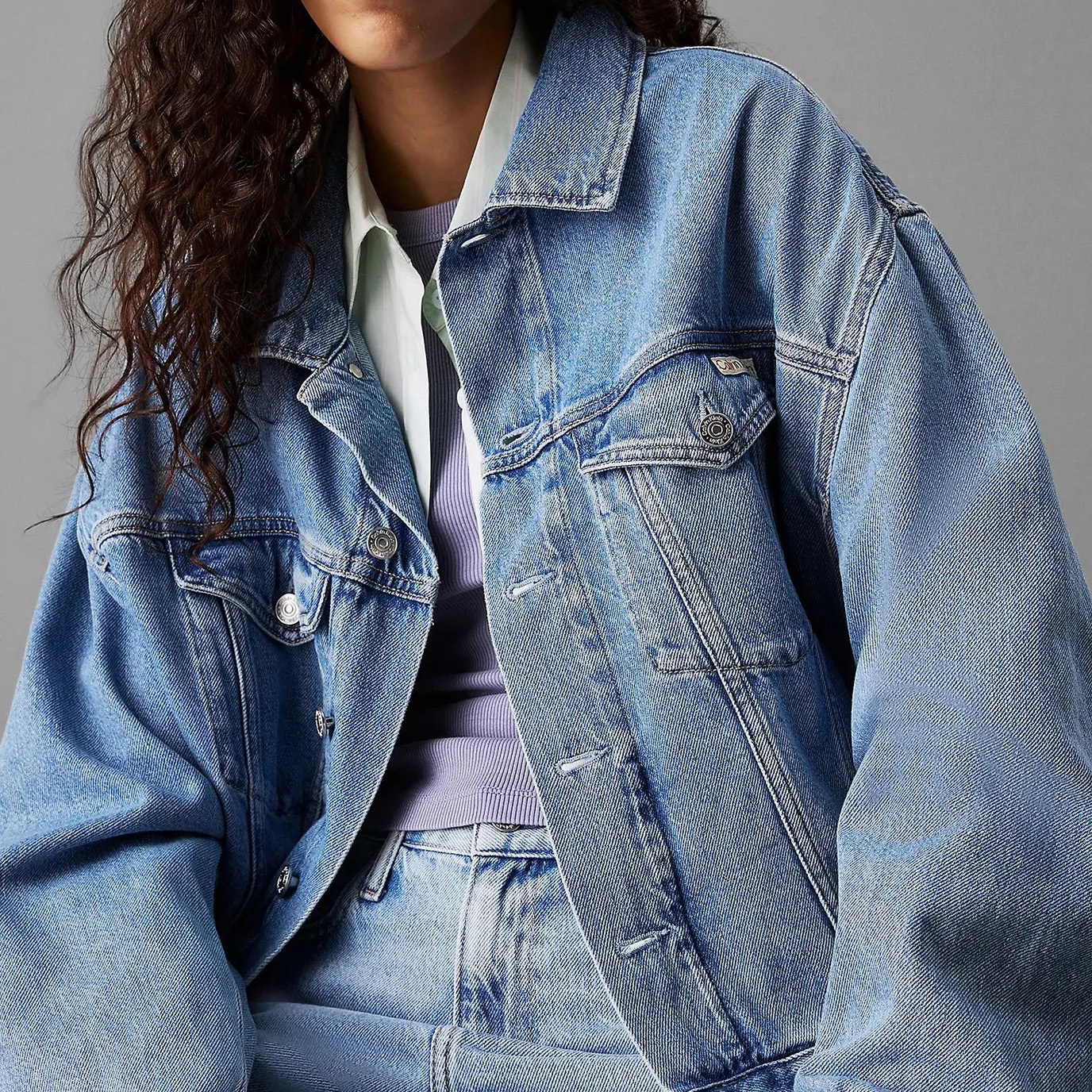 Casaco de ganga azul claro com botões metálicos.