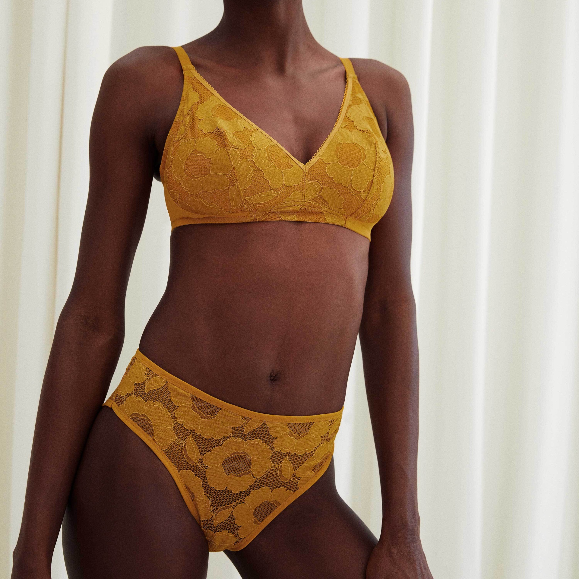 Conjunto de lingerie amarelo mostarda em renda floral com soutien e cueca, modelo em fundo branco