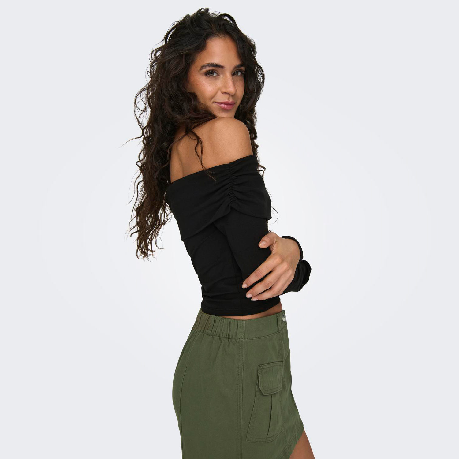 Mulher com camisola preta ombro a ombro e saia verde cargo