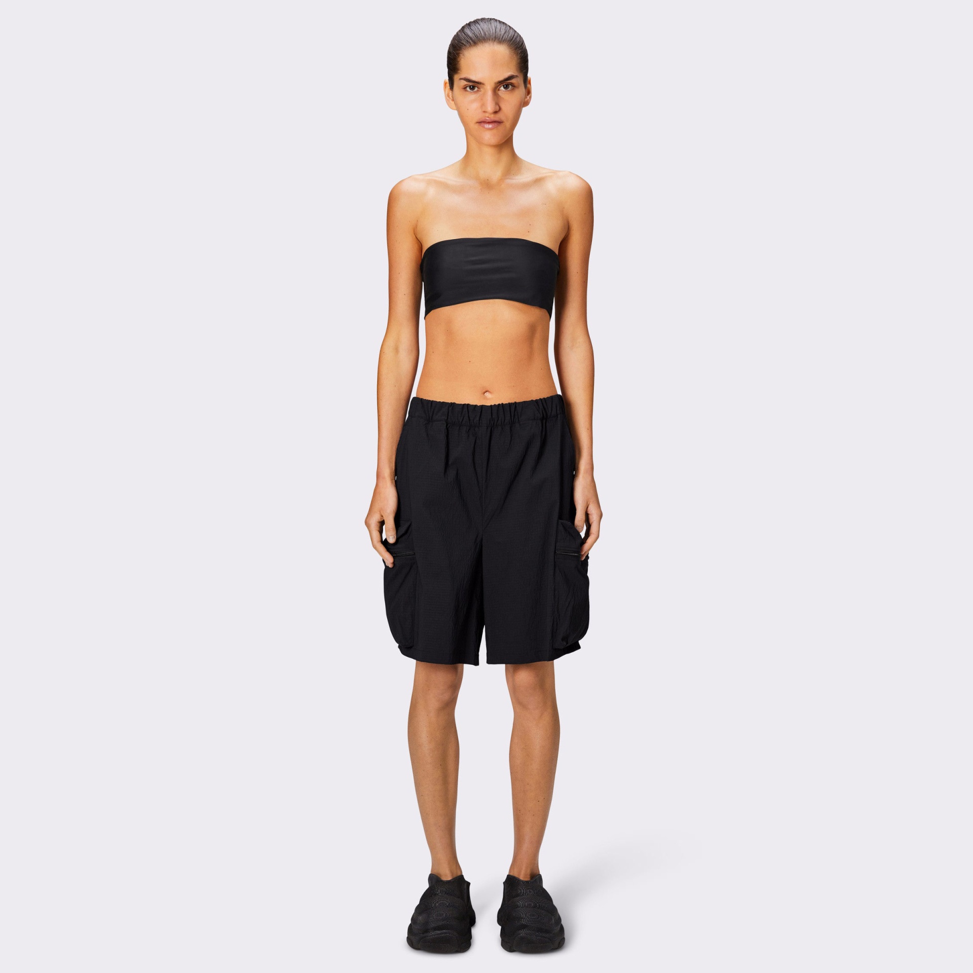 Modelo com top bandeau preto, calções pretos com bolsos grandes e ténis pretos