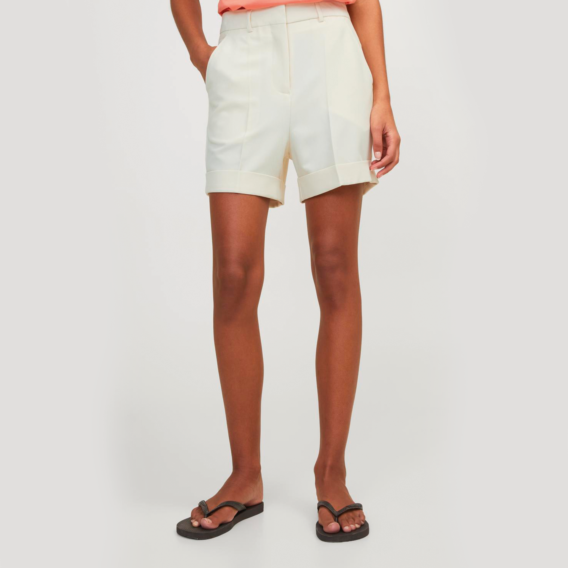 Calções brancos com dobra na bainha usados por uma pessoa em estúdio branco