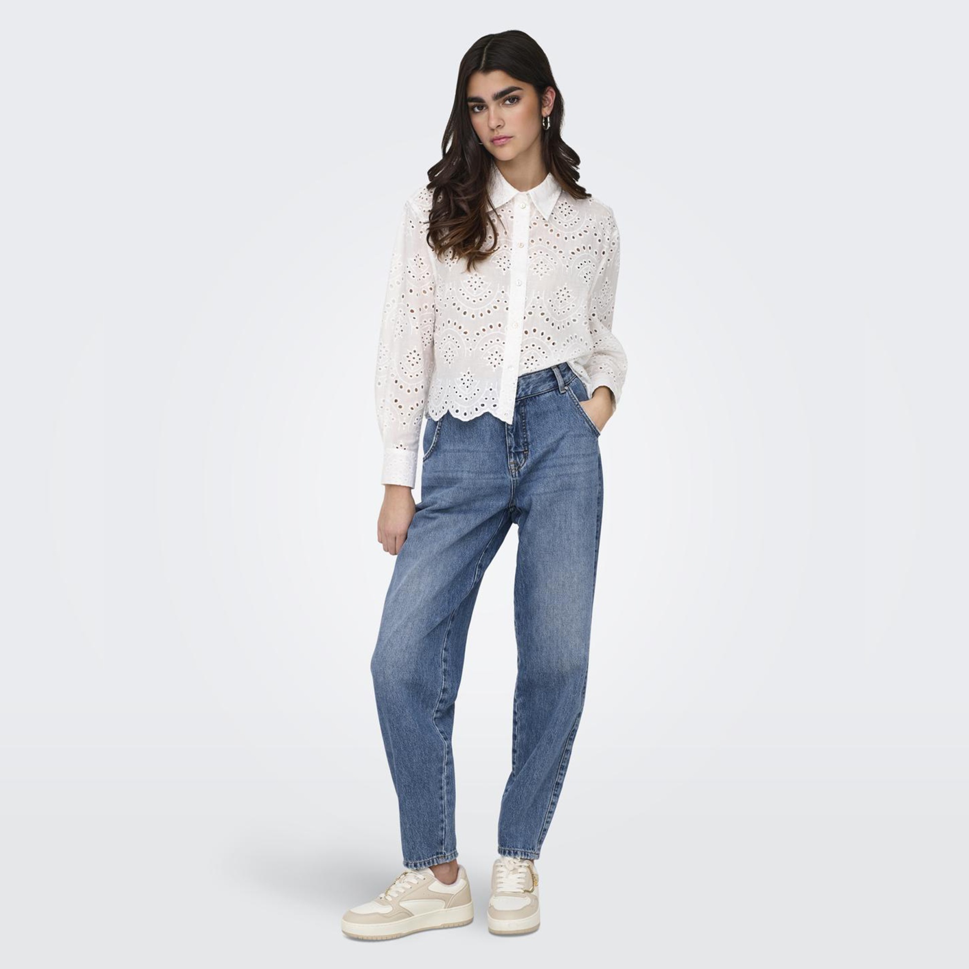 Camisa branca bordada com calças de ganga azuis e ténis brancos