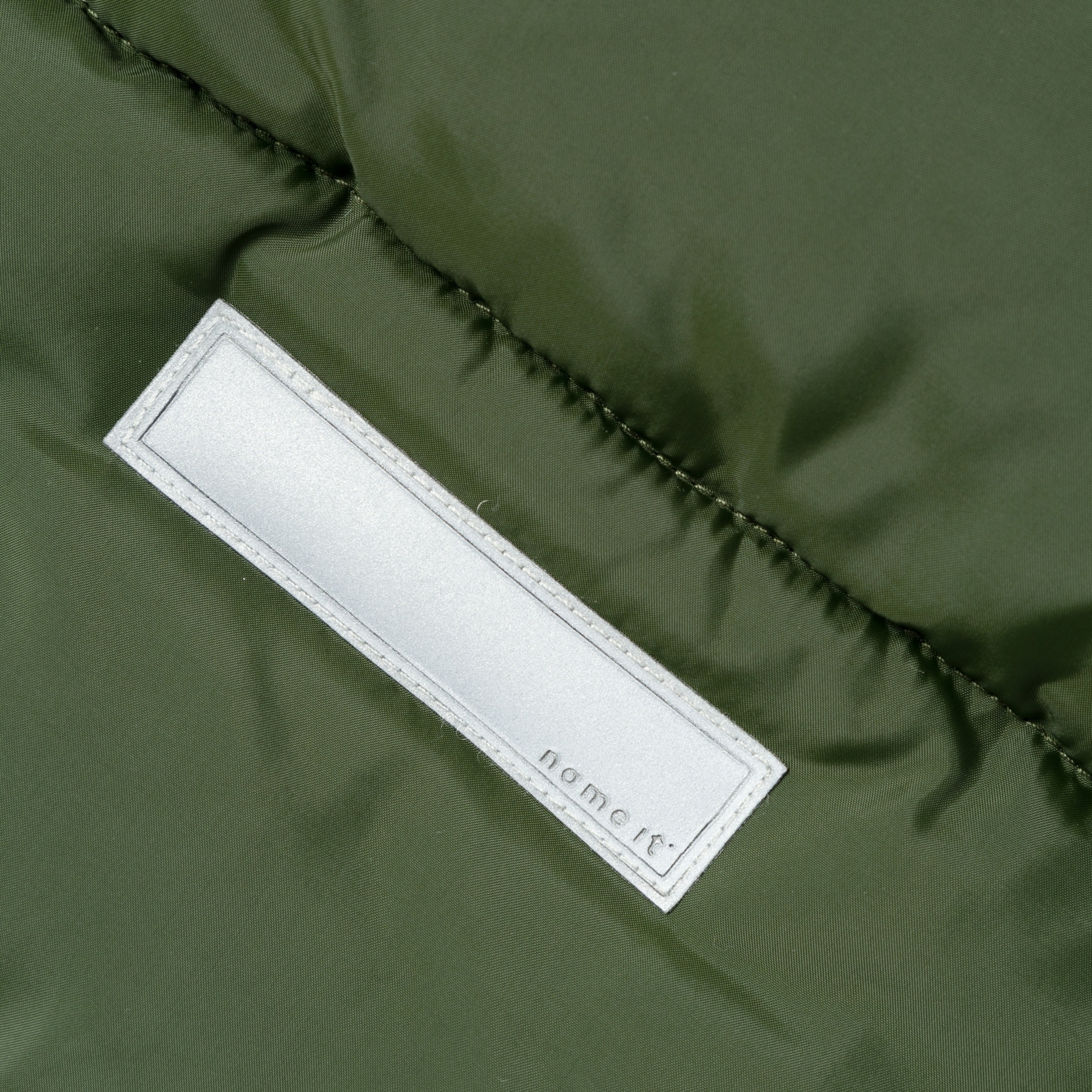 Etiqueta branca com texto name it em tecido verde escuro