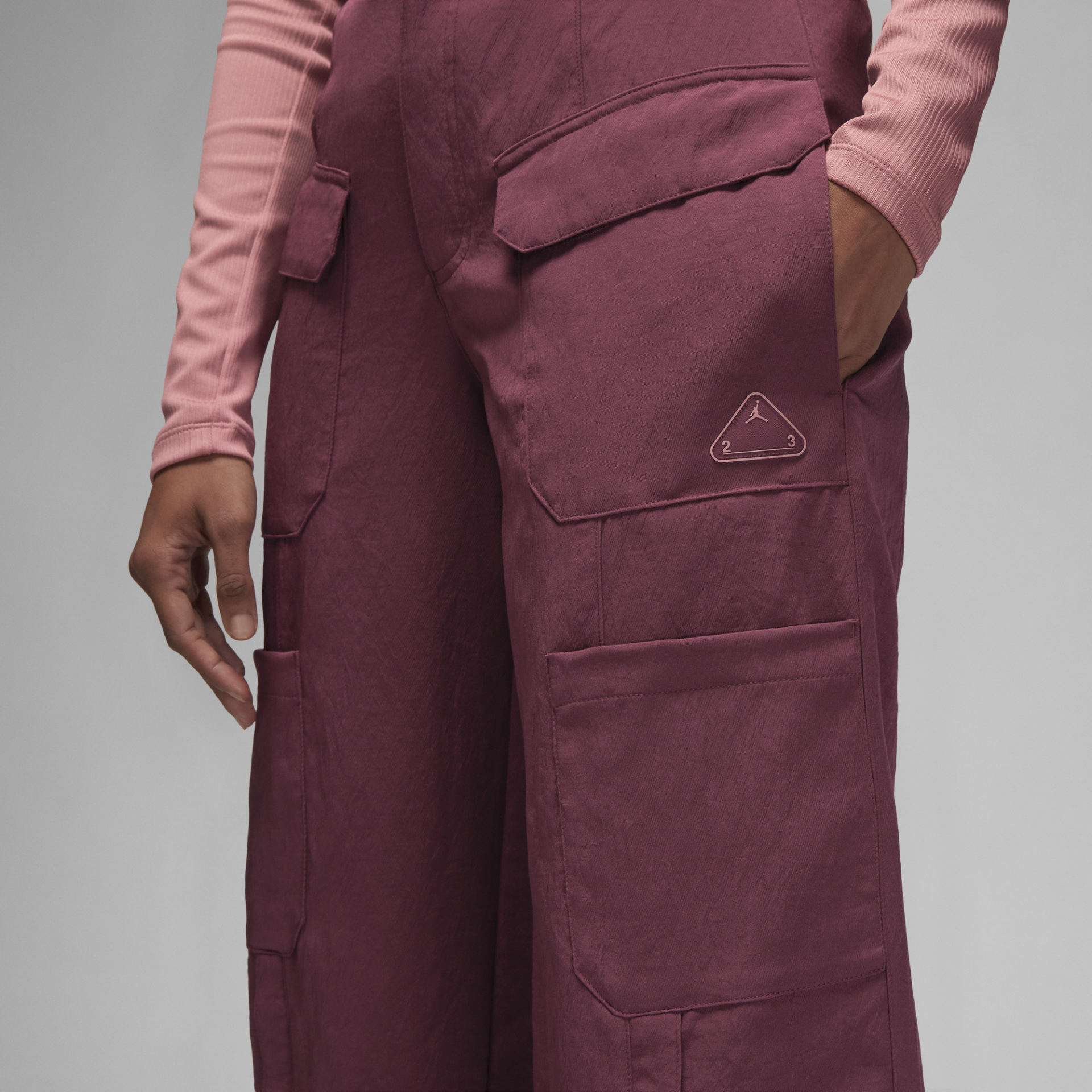 Calças cargo roxas com bolsos e logótipo triangular numa pessoa com camisola rosa