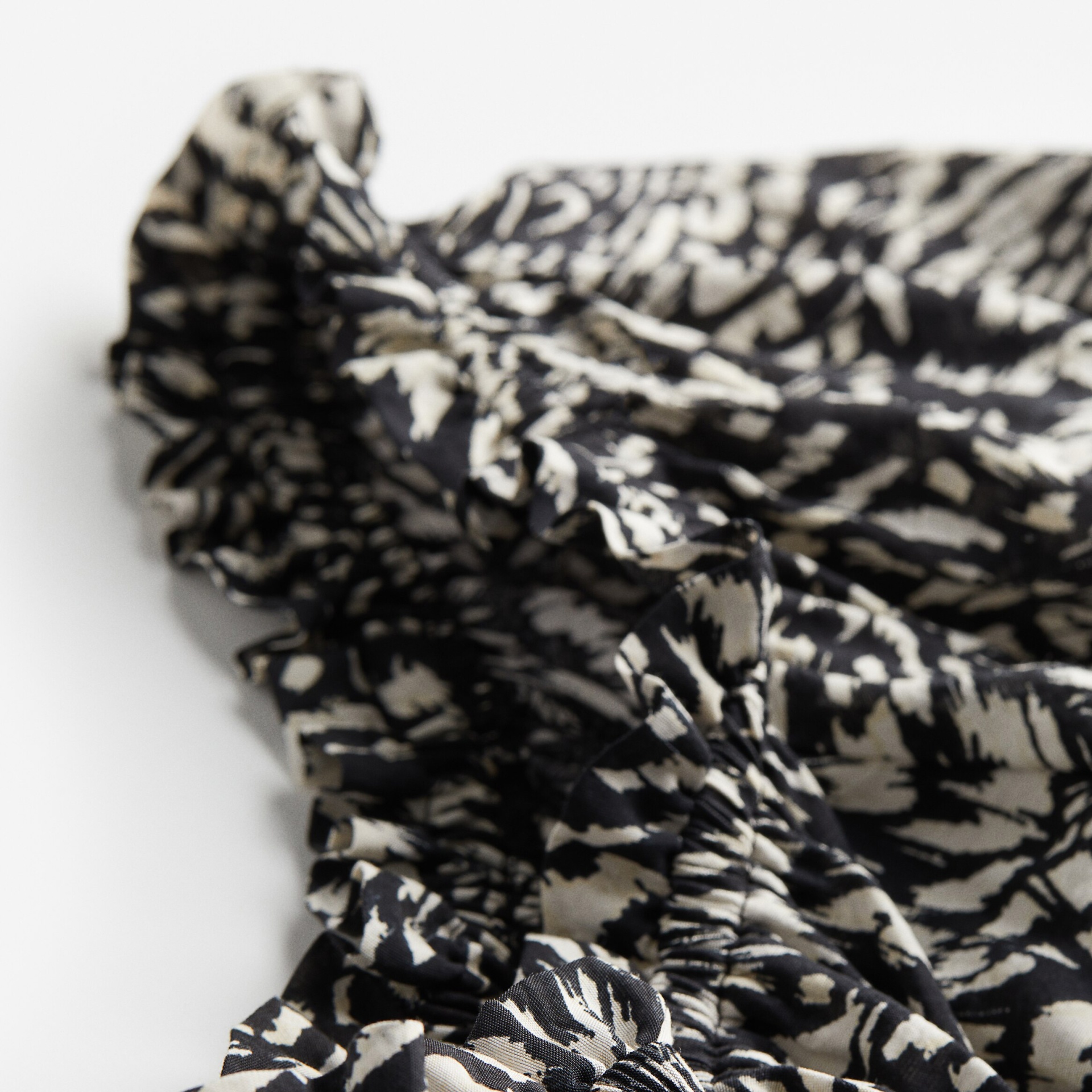Tecido preto e branco com padrão abstrato numa superfície branca