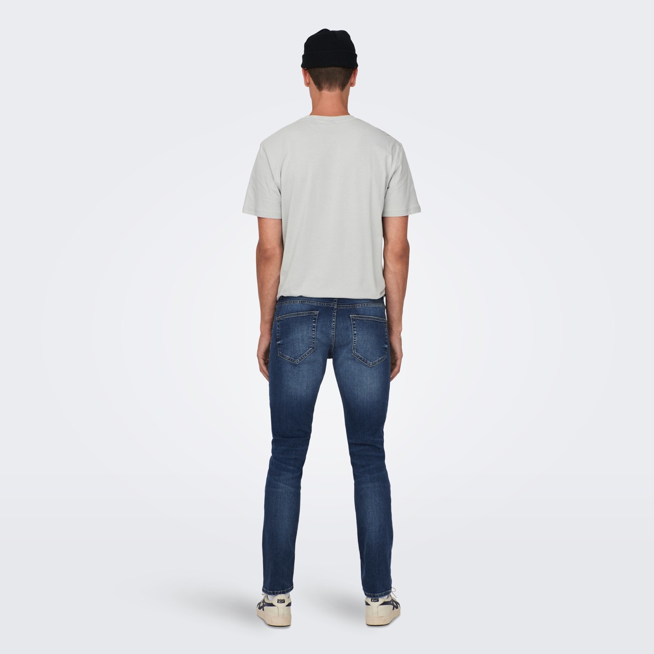 Homem de costas com t-shirt cinza e calças de ganga azul