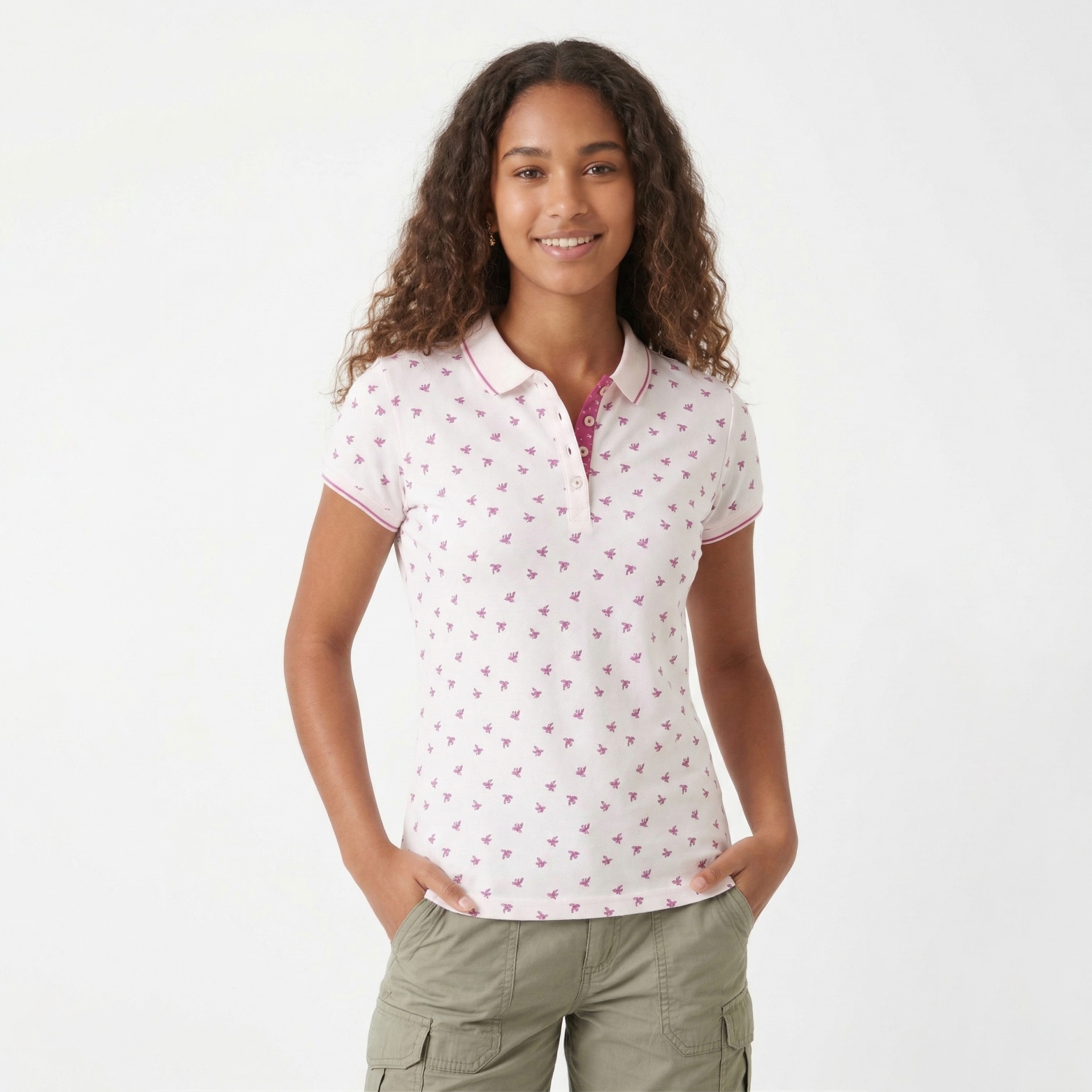 Mulher a usar polo branco com padrão cor-de-rosa e calças verdes.