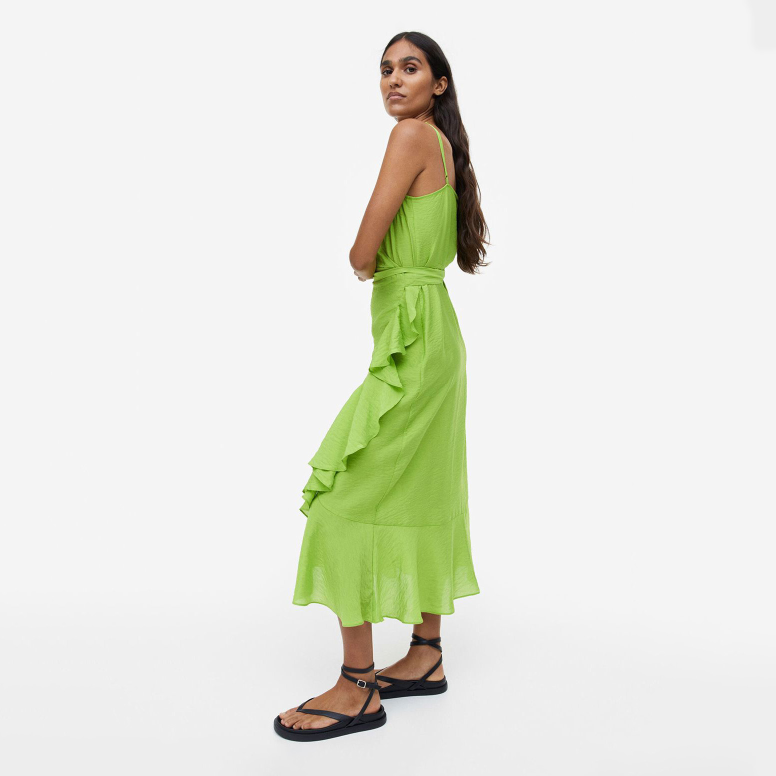 Mulher vestindo vestido midi verde com folhos e sandálias pretas
