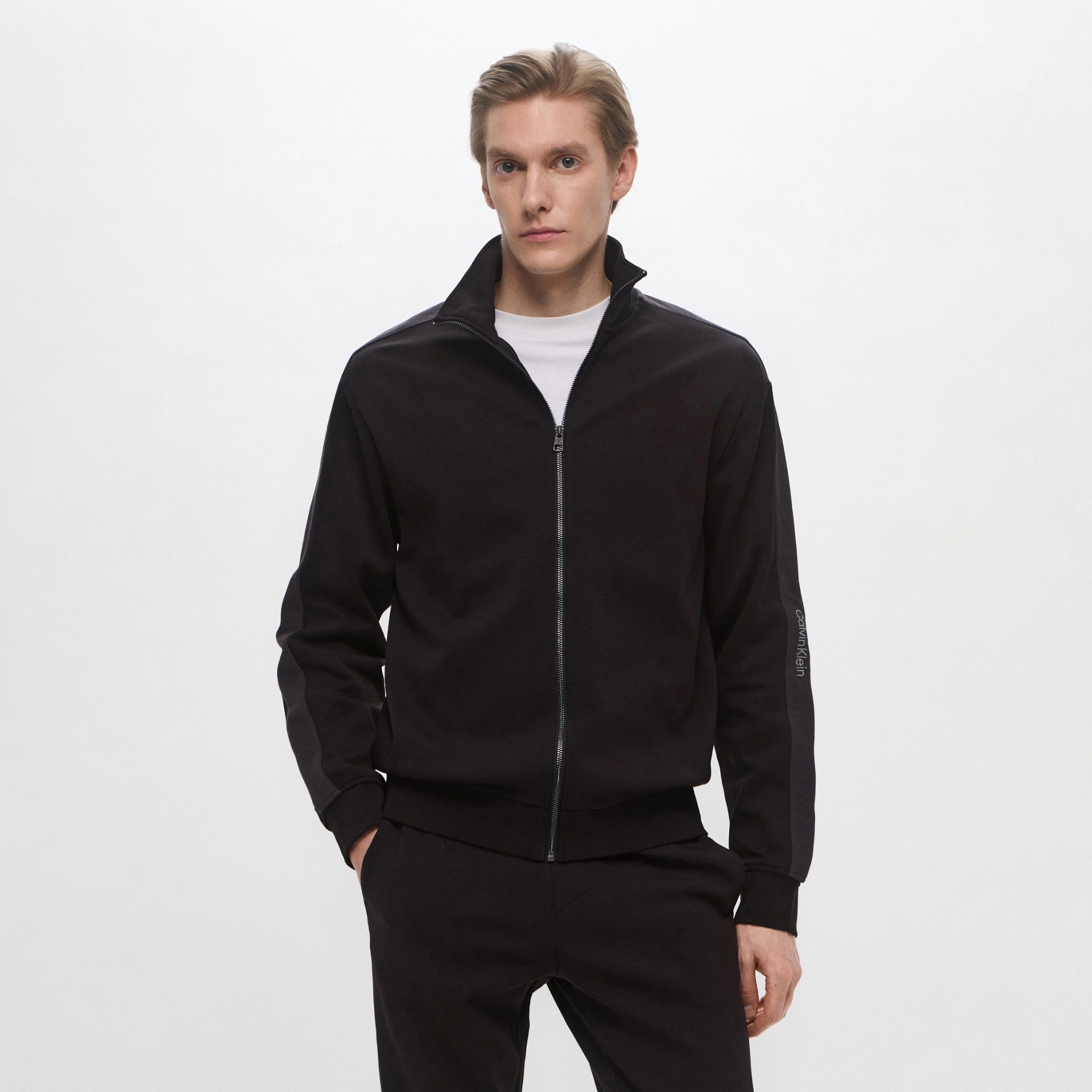 Homem com casaco preto de fecho e marca calvin klein na manga