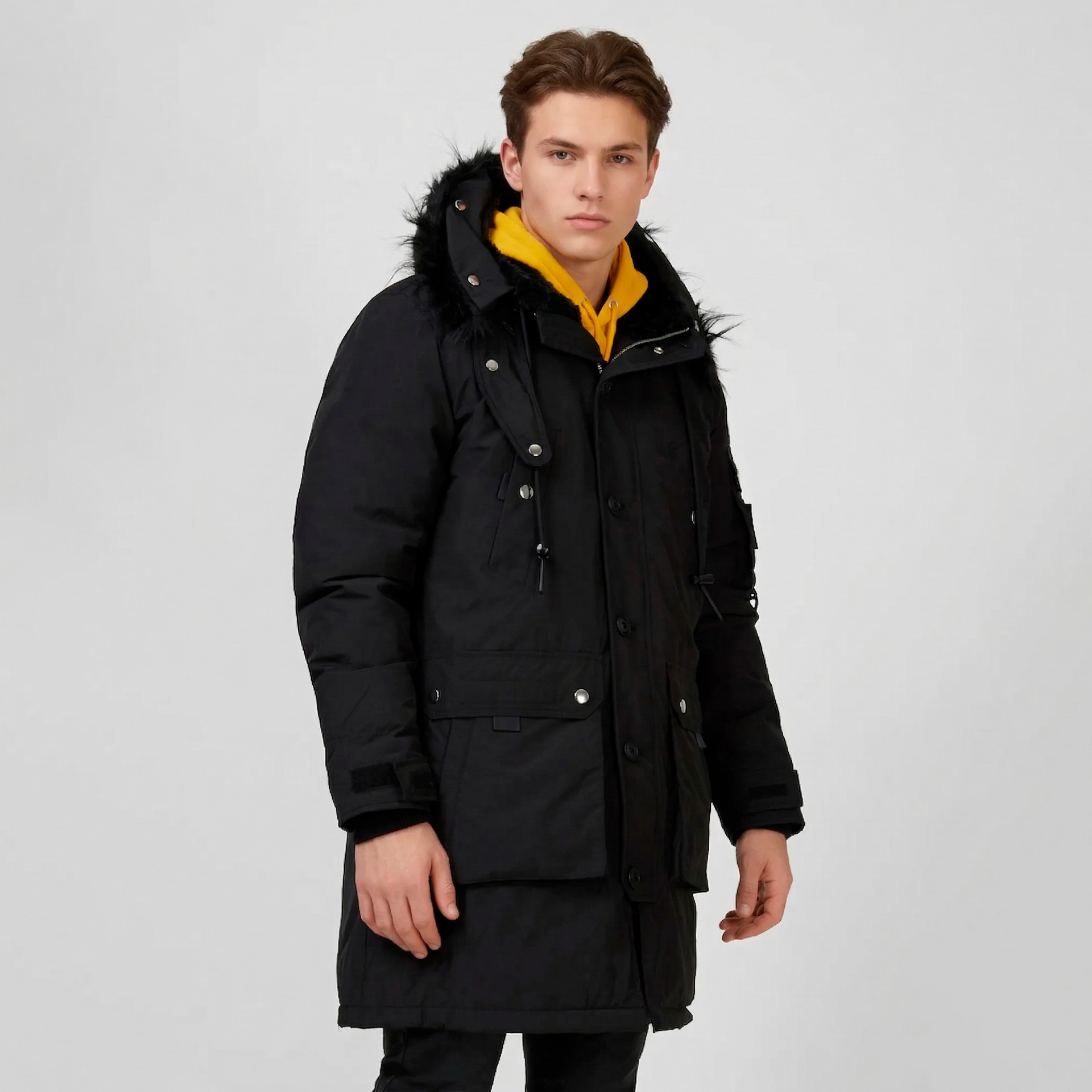 Casaco parka preto com capuz e pêlo usado por homem com camisola amarela
