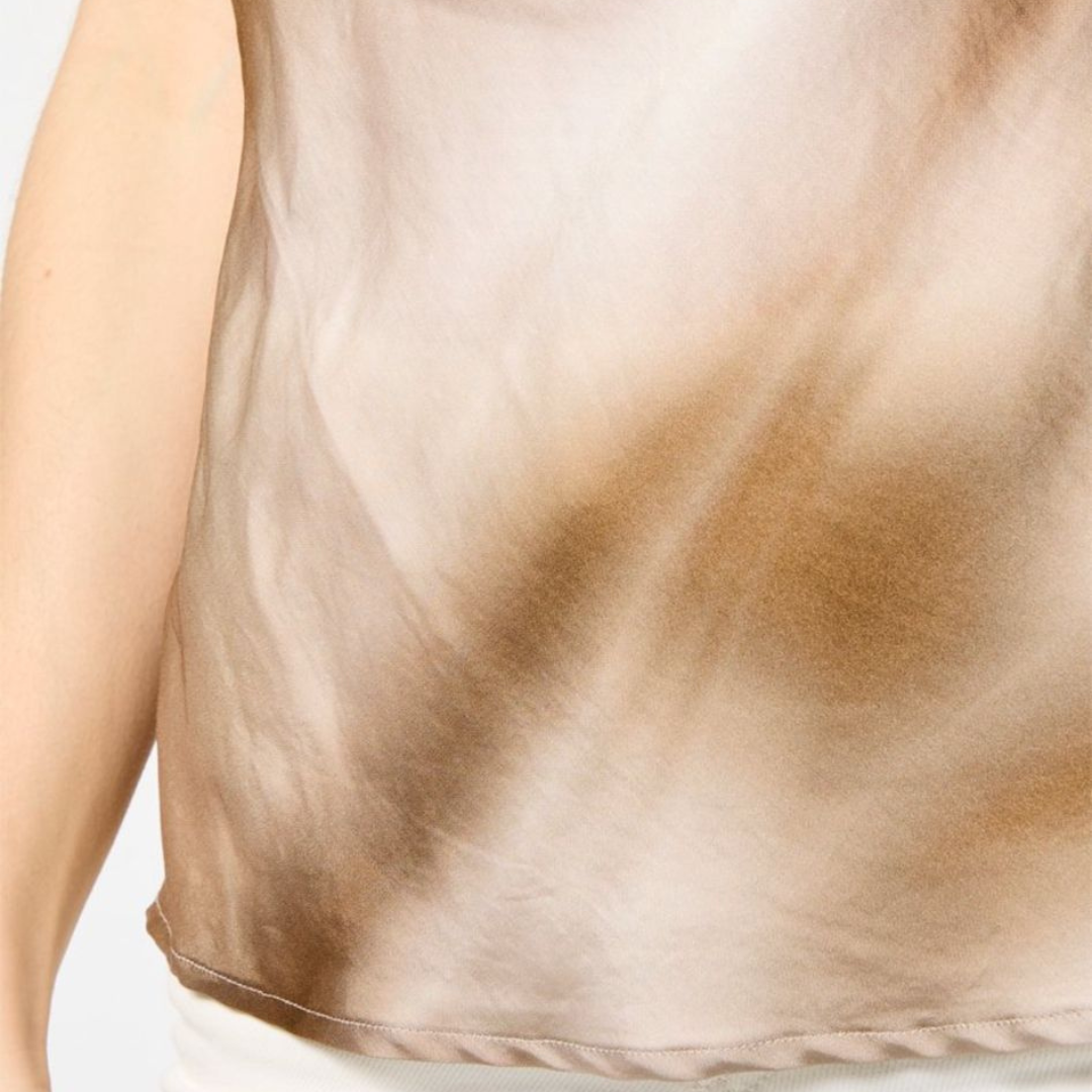 Detalhe de peça de vestuário castanha e bege com padrão ondulado