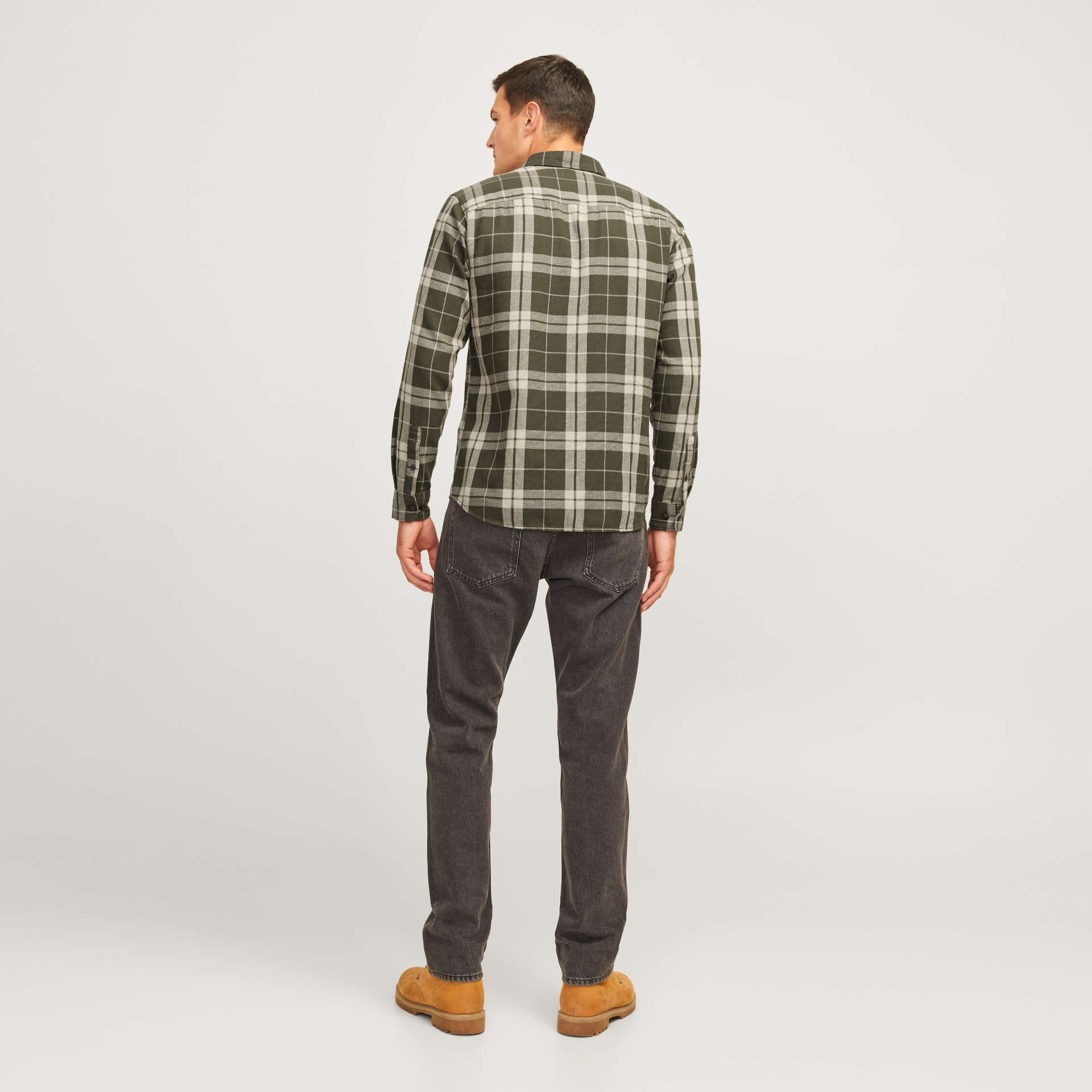 Camisa xadrez verde e branca vista de costas com calças pretas e sapatos castanhos