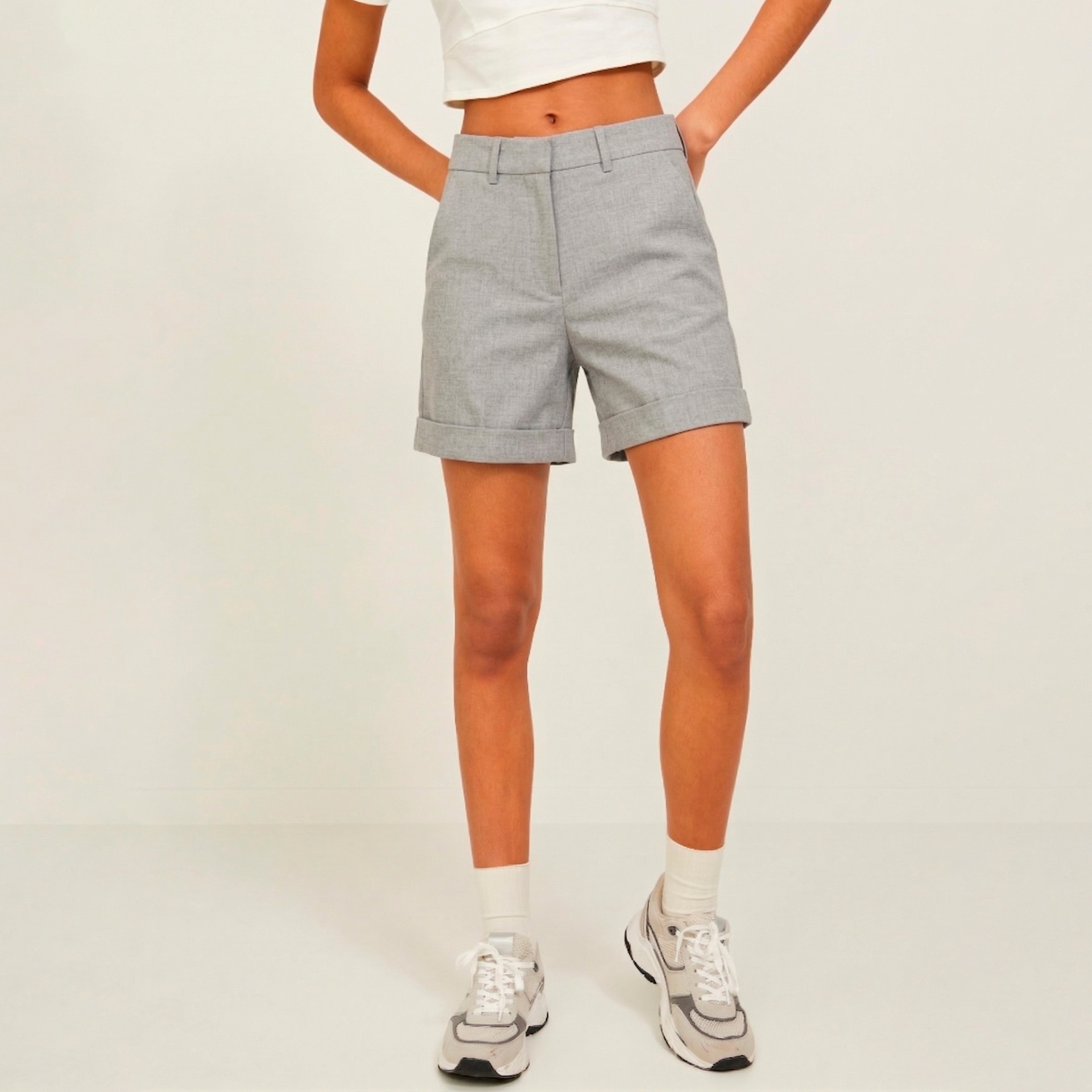 Pessoa com calções cinza, top branco, meias e sapatilhas brancas