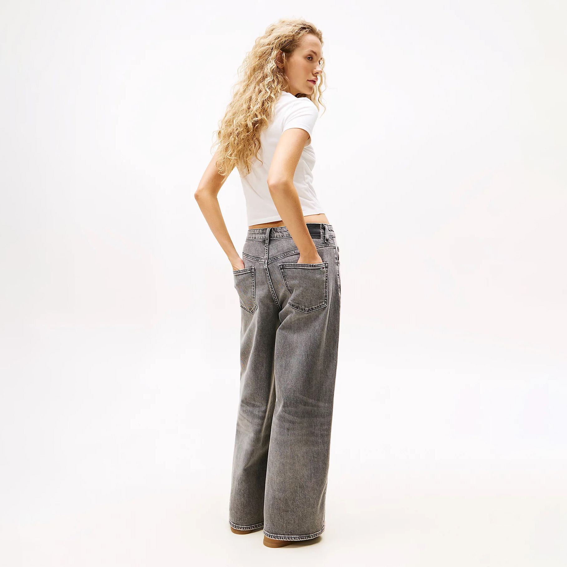 Mulher de costas com t-shirt branca e calças largas de ganga cinzenta