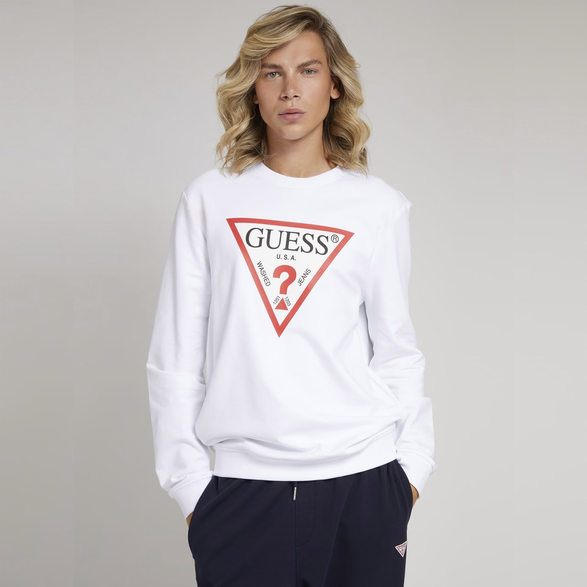 Pessoa a usar sweatshirt branca com logótipo GUESS U.S.A. triangular vermelho e preto