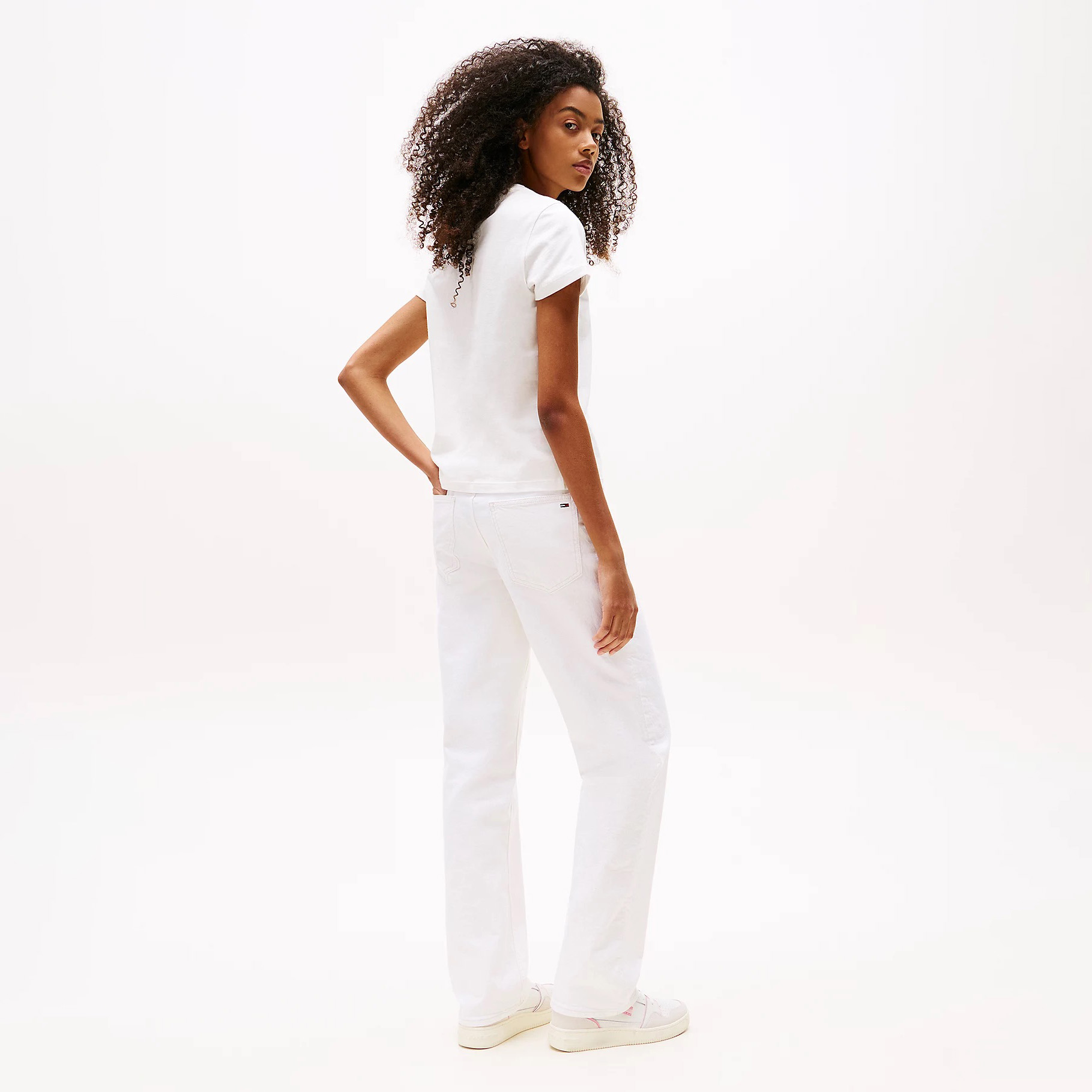 Mulher de costas com t-shirt branca, calças brancas e ténis brancos