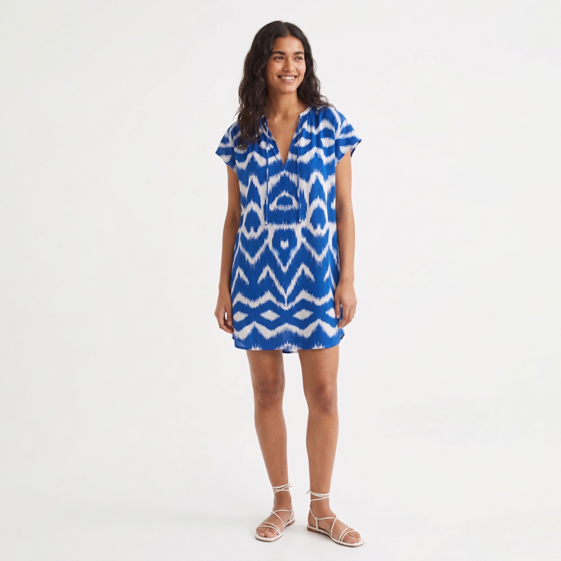 Vestido azul e branco padrão zig-zag, mulher a sorrir e sandálias brancas