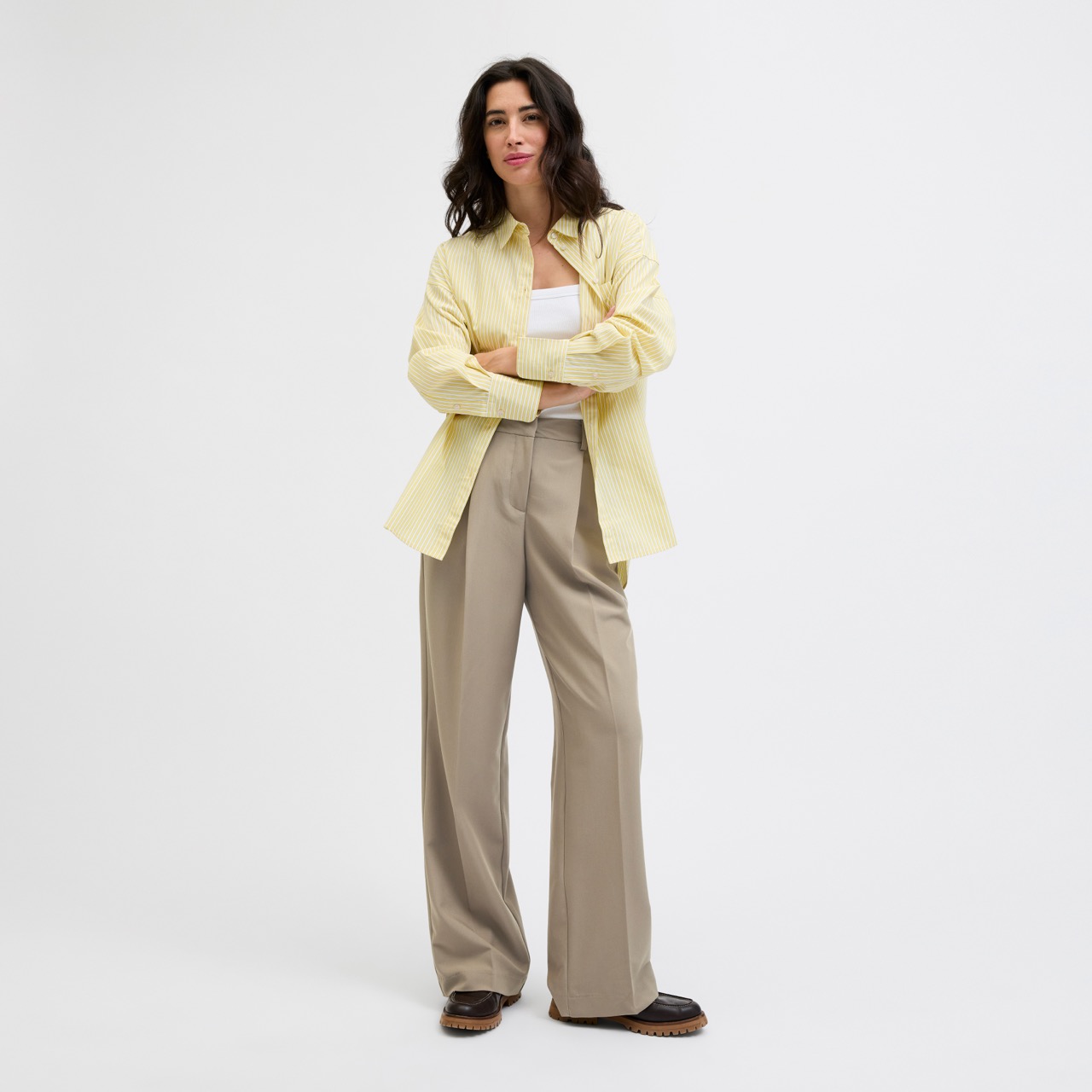 Mulher com camisa amarela, t-shirt branca e calças largas bege