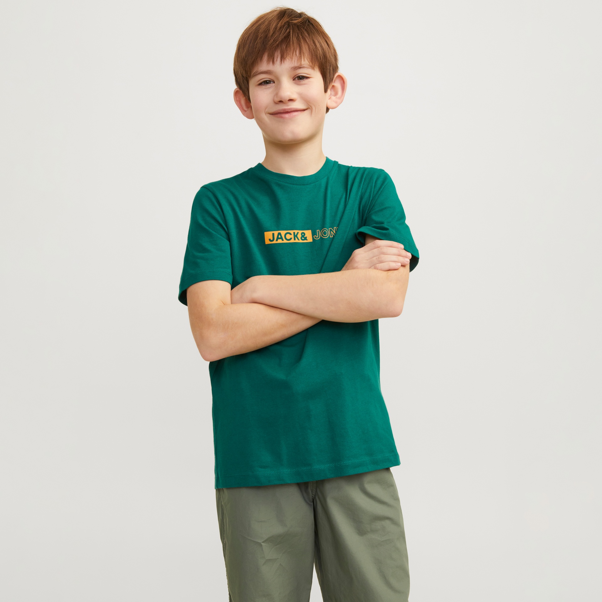 Rapaz com t-shirt verde Jack&JON e calças verde-oliva em fundo branco.