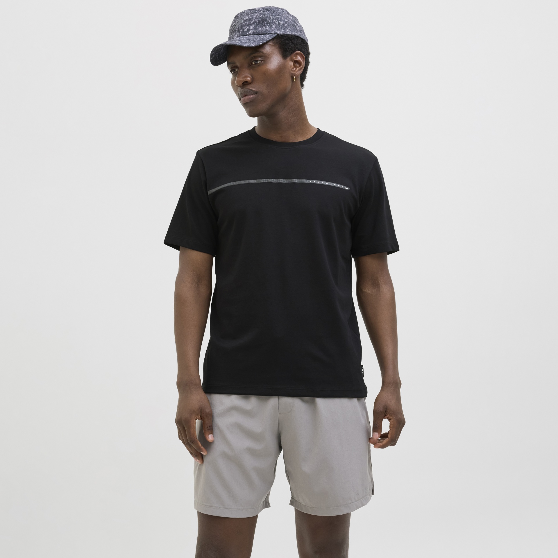Homem com t-shirt preta, calções cinza claro e boné cinza com padrão marmoreado