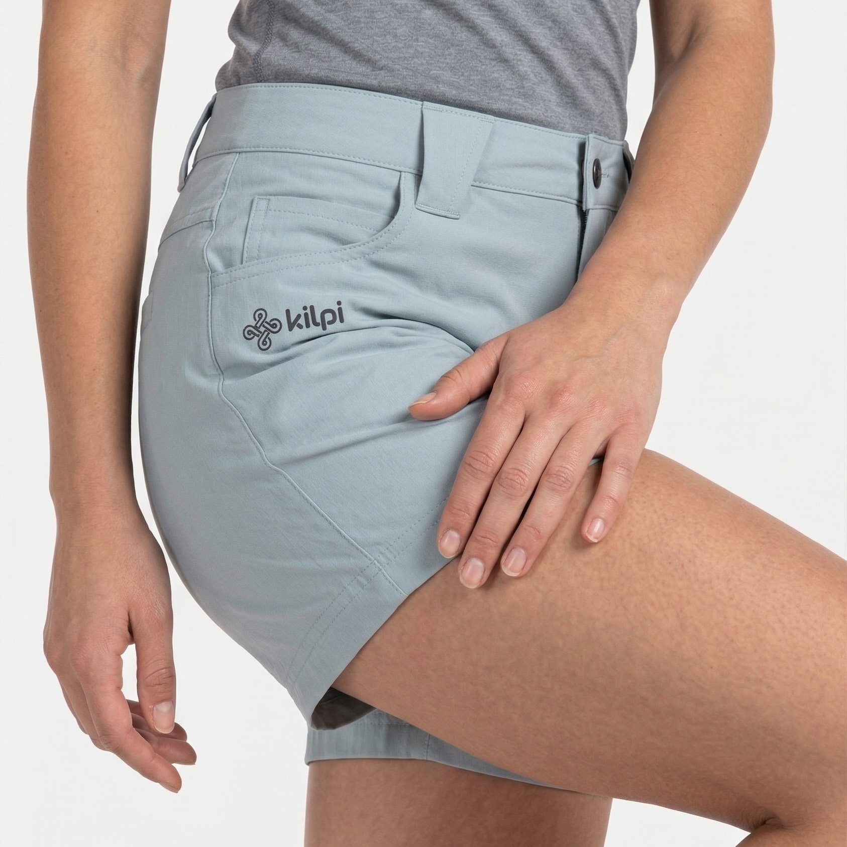 Calções azuis claros com logo kilpi ao lado de uma pessoa com t-shirt cinzenta