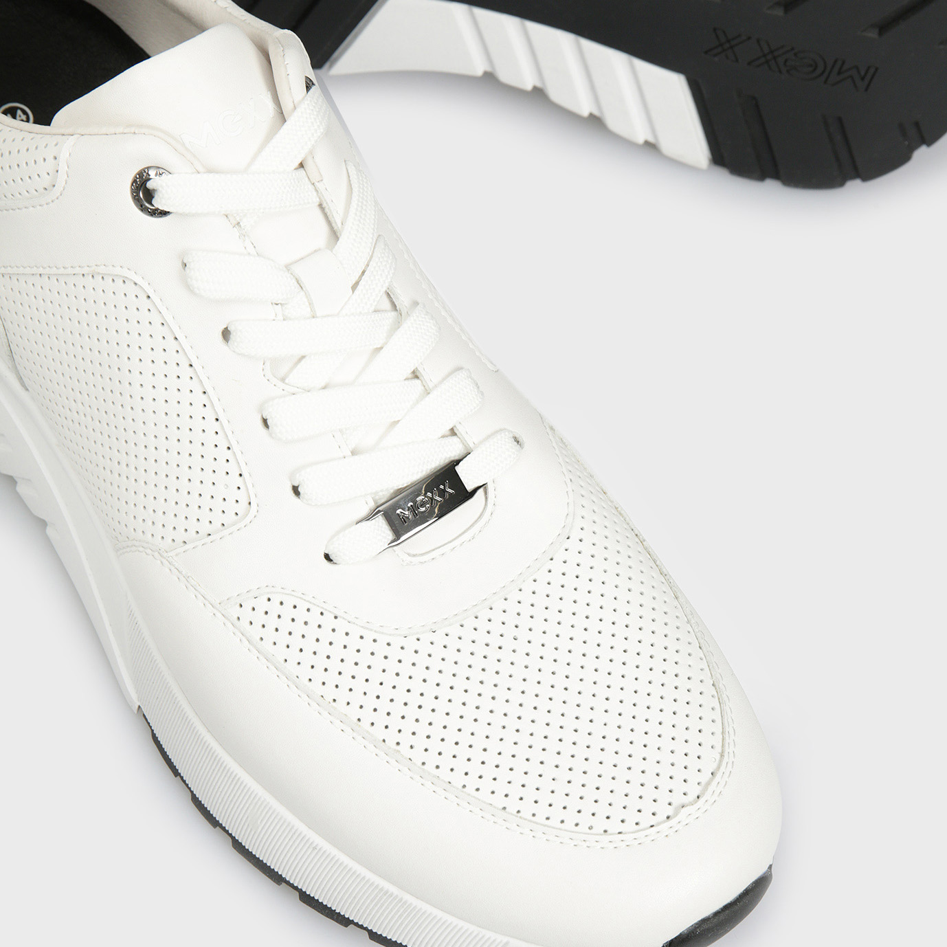 Tênis branco com detalhes perfurados e sola preta e branca