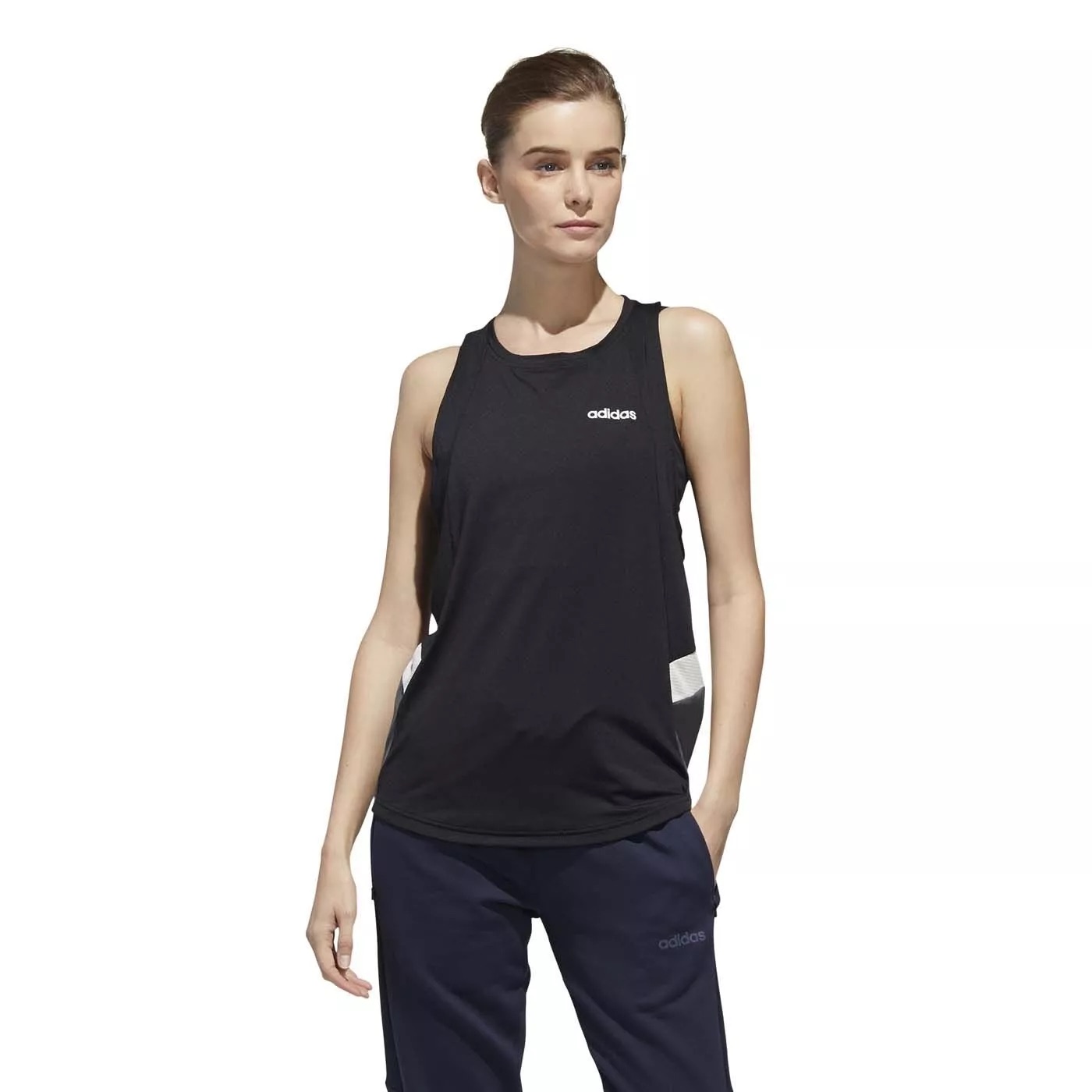 Mulher com top preto adidas e calças azuis escuras adidas