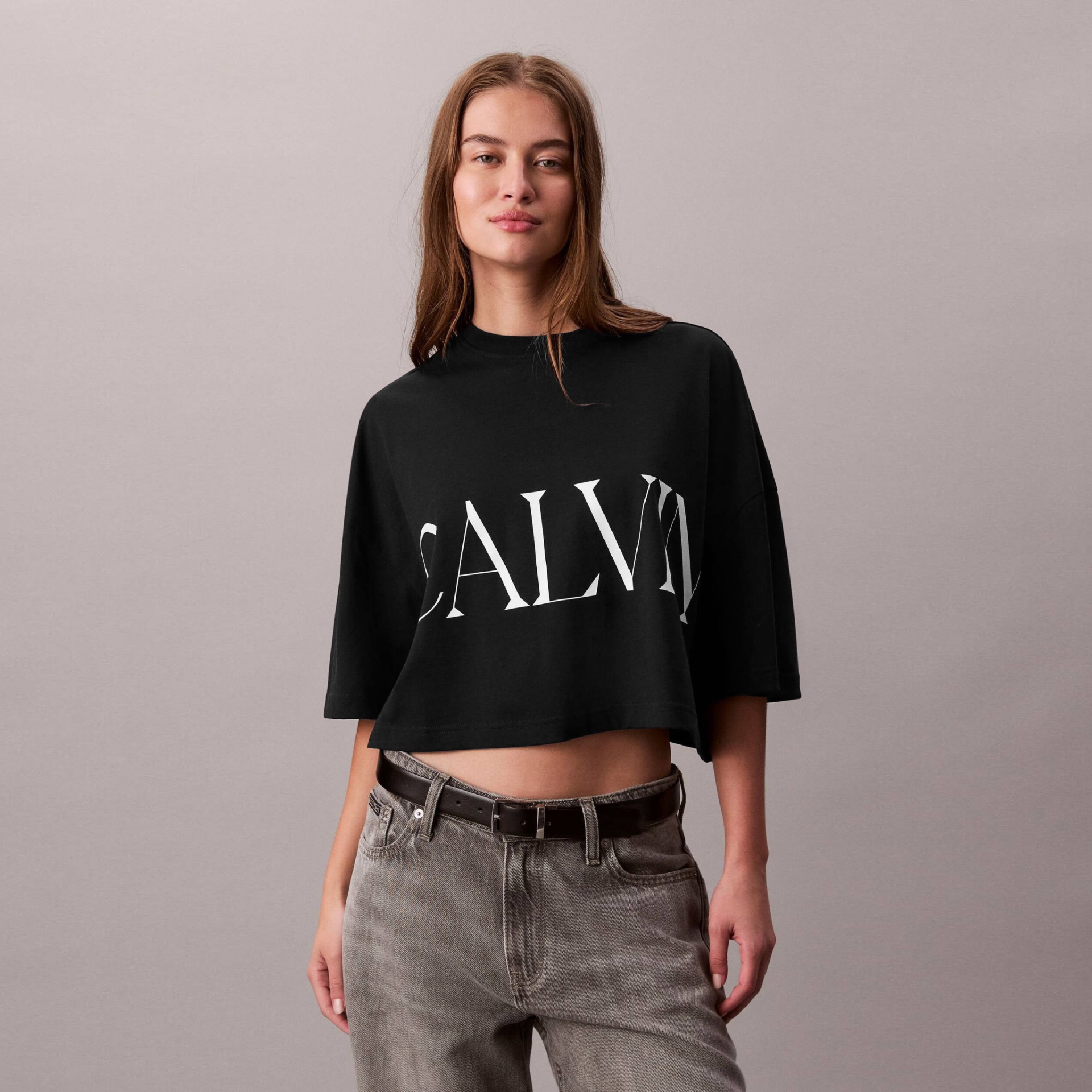 Camisola preta cropped com texto CALV e calças jeans cinzentas