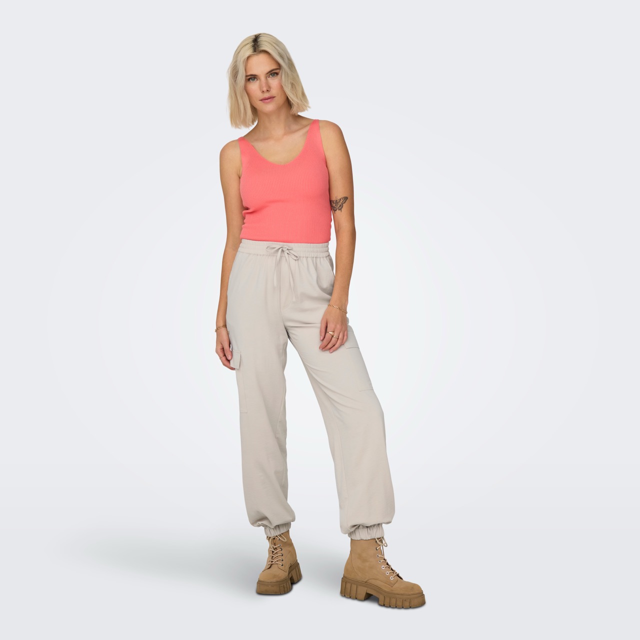 Pessoa com roupa casual cor-de-rosa, bege e castanha, em fundo branco