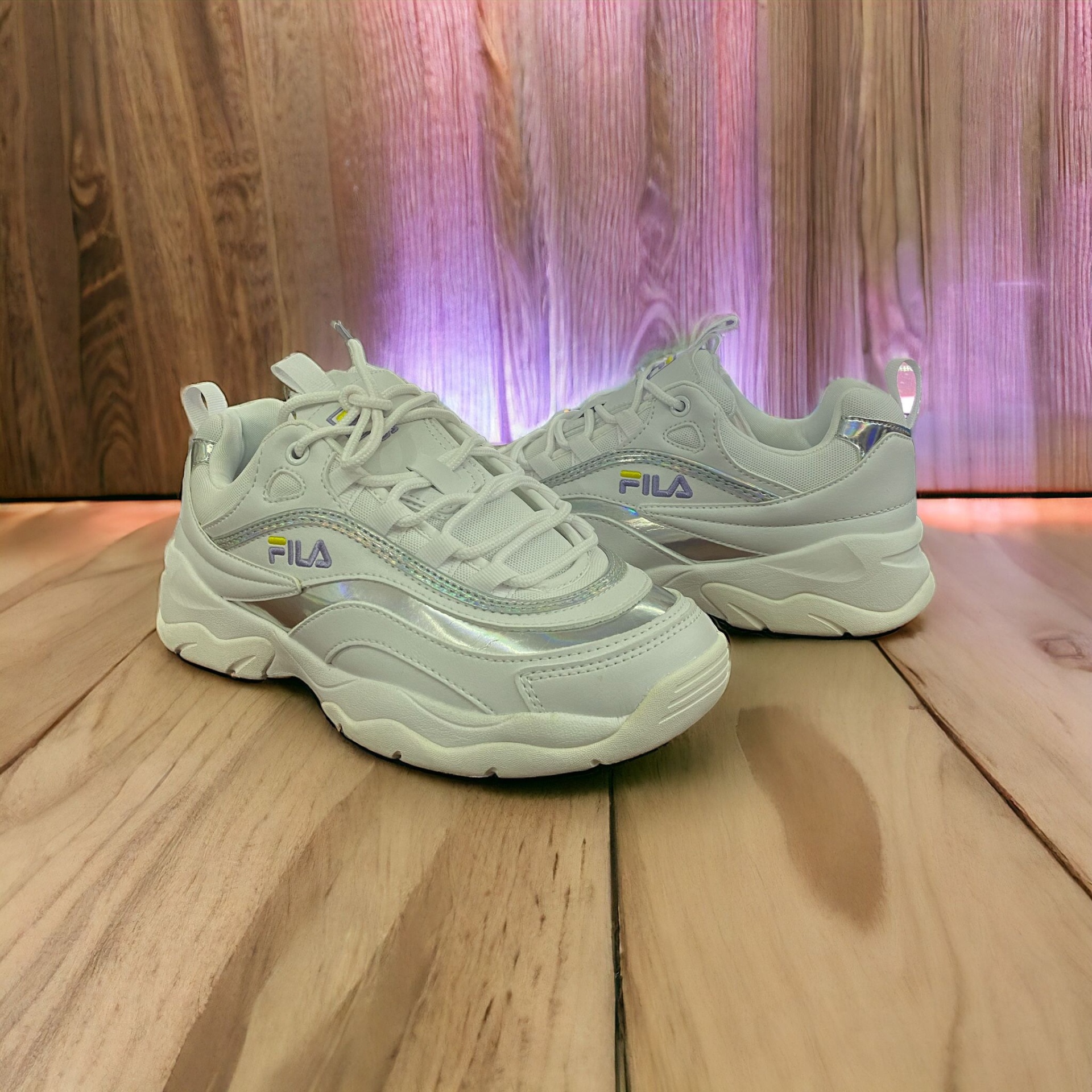 Ténis FILA brancos com detalhes cinza e lilás em superfície de madeira