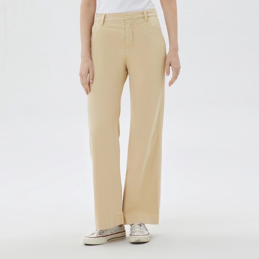 Calças compridas bege e sapatilhas brancas em fundo branco