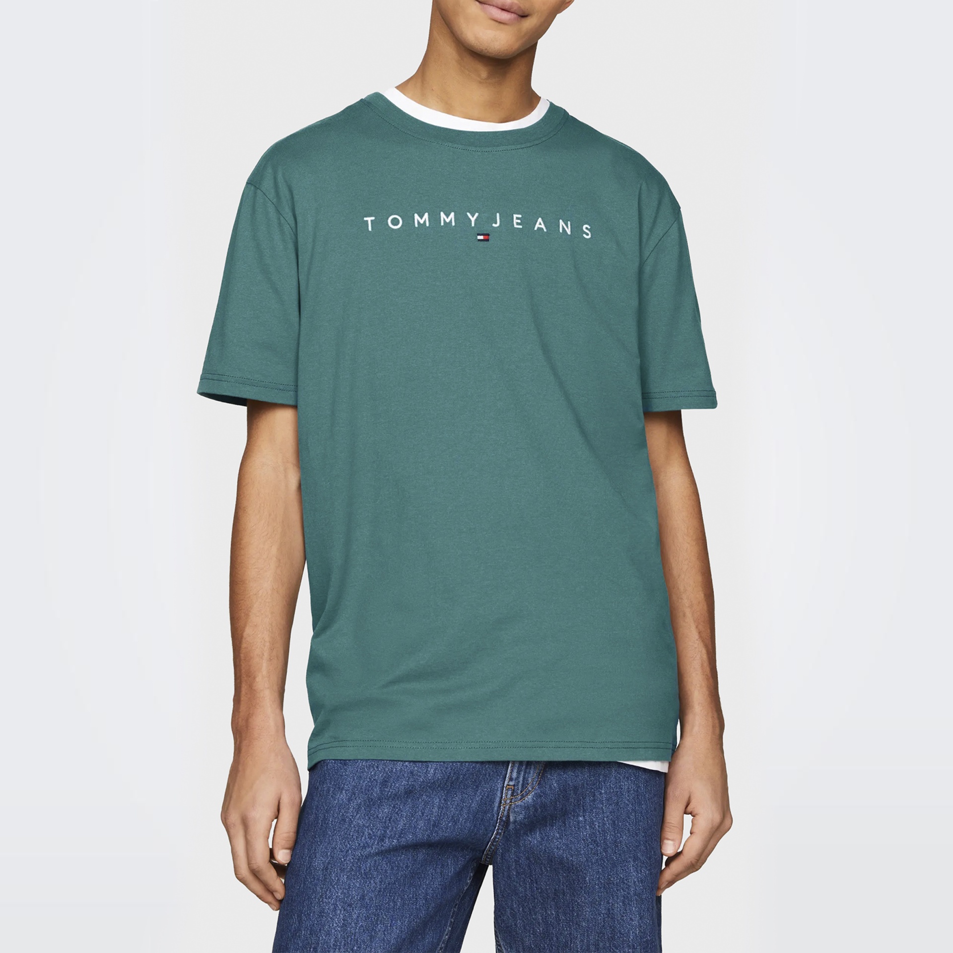 T-shirt verde com texto 'TOMMY JEANS' e calças de ganga azuis