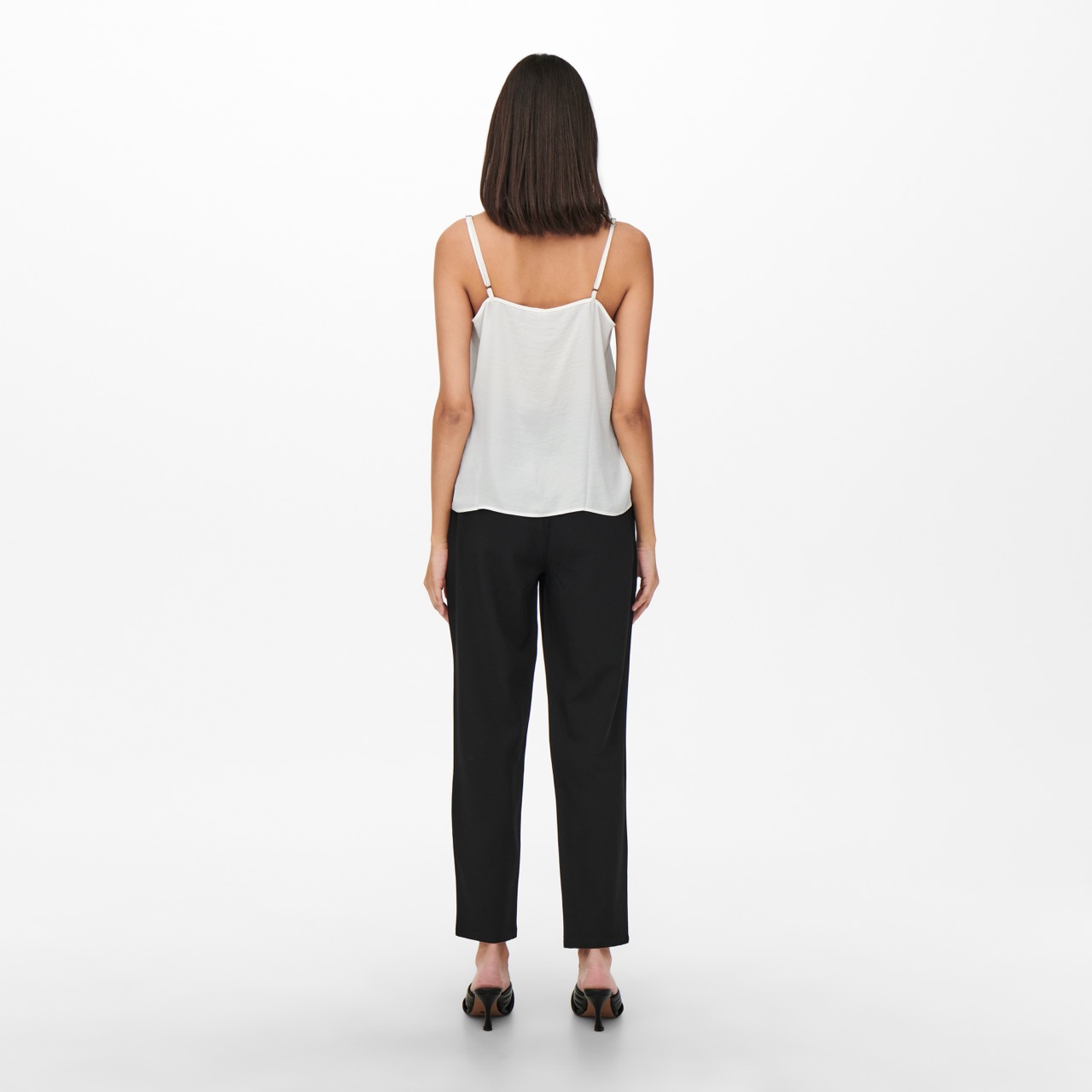 Mulher vista de costas com top branco de alças finas e calças pretas compridas