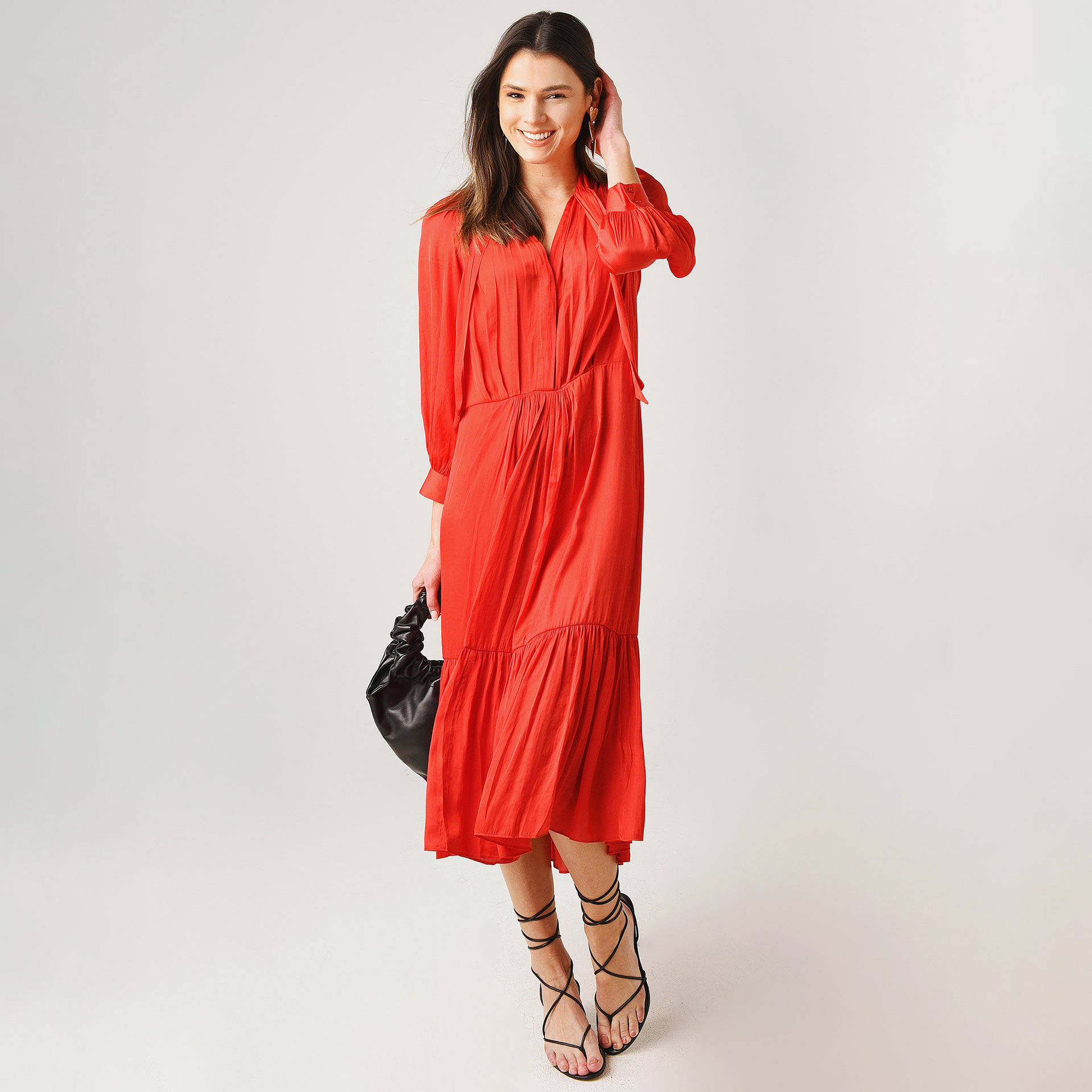 Mulher de vestido vermelho, bolsa preta e sandálias pretas com tiras finas cruzadas