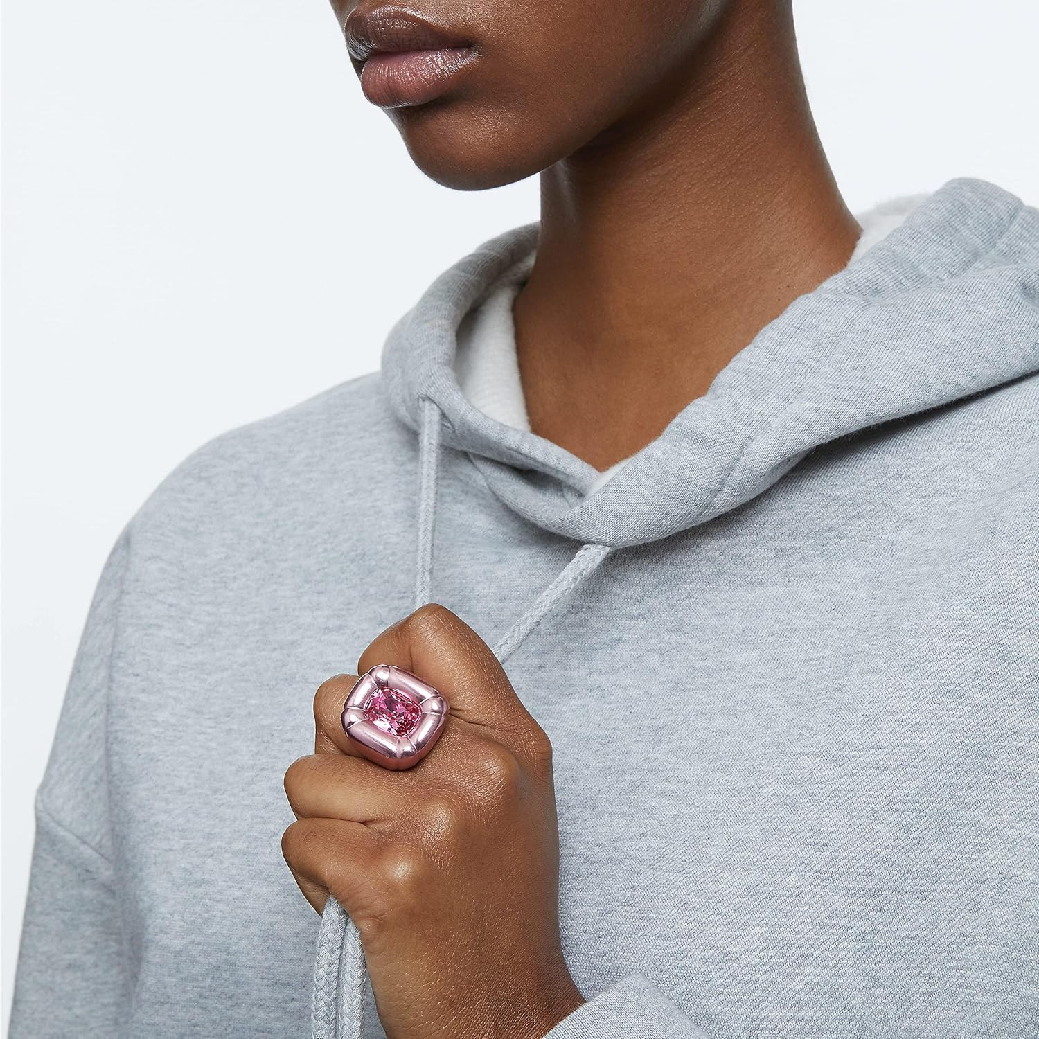 Mão com anel rosa metálico e sweat cinzento