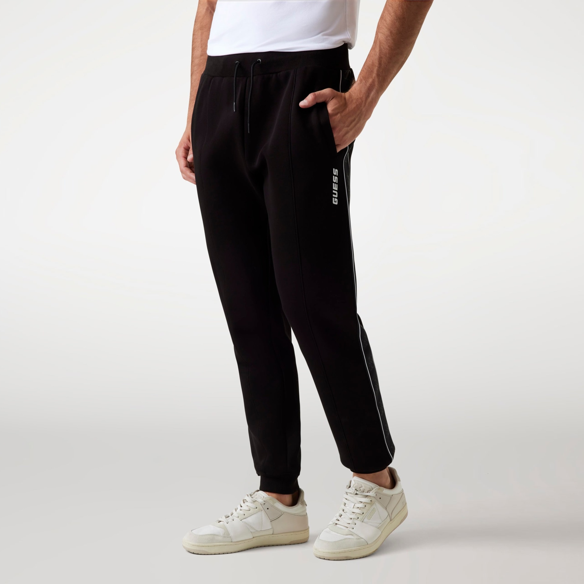 Calças de treino pretas com texto GUESS vertical na perna