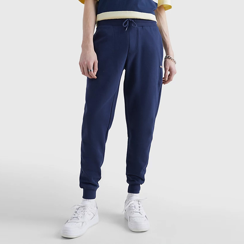 Calças de treino azuis escuras com ténis brancos.