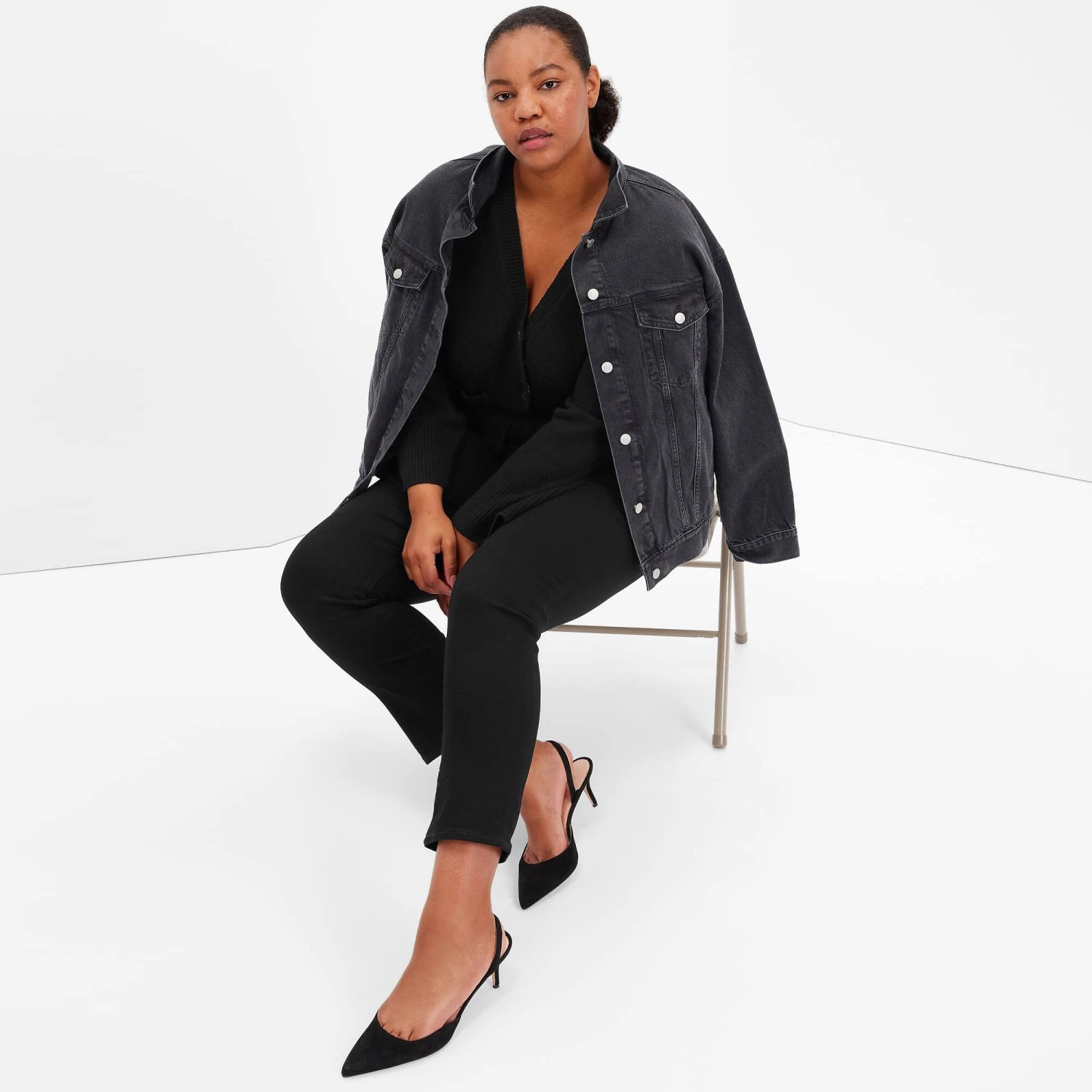 Mulher sentada com casaco de ganga preto e roupa preta