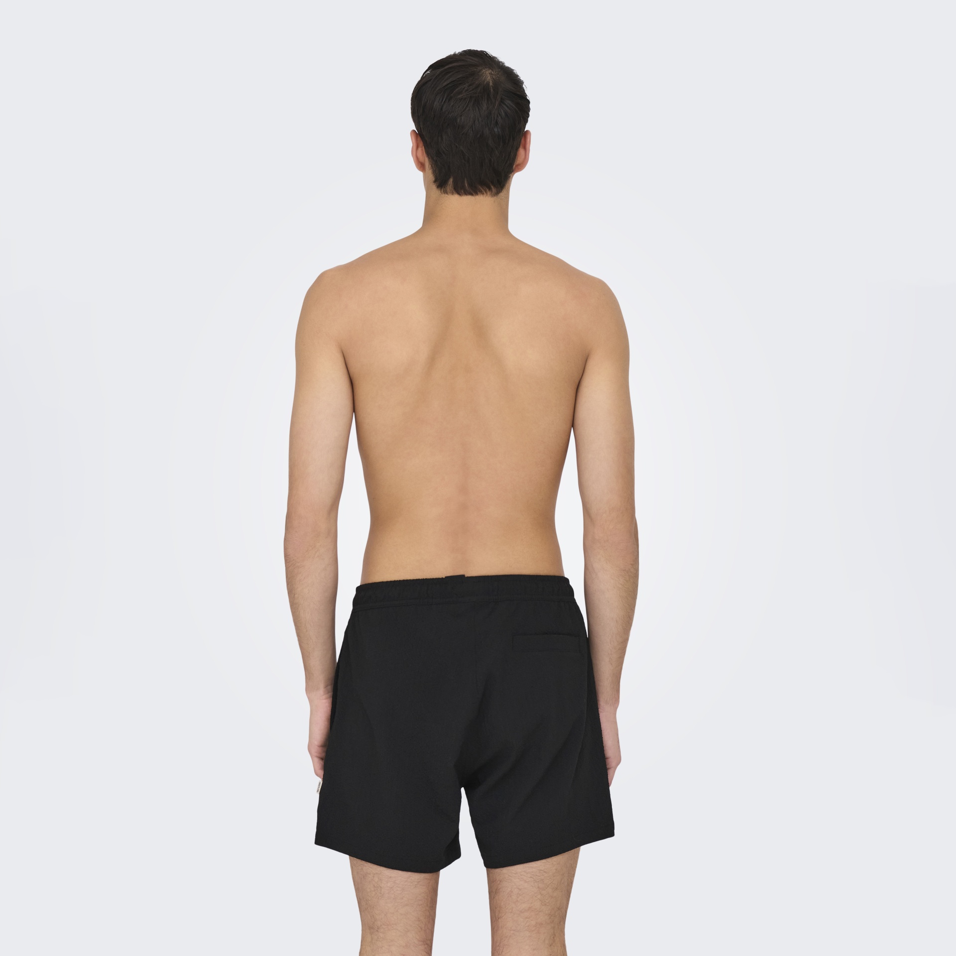 Homem de costas sem camisa usando calções pretos