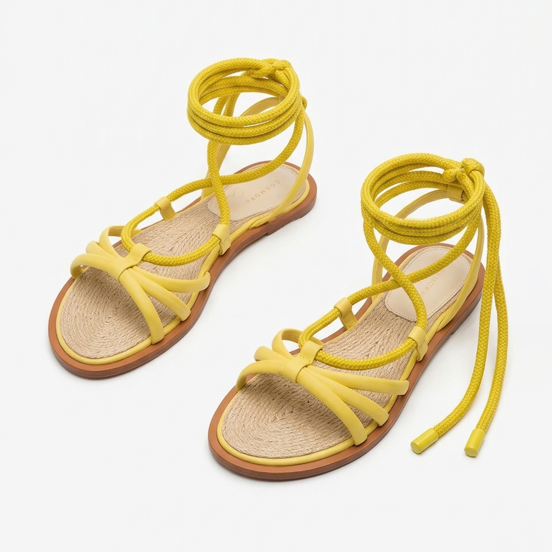 Sandálias amarelas com tiras de corda e sola castanha num fundo branco