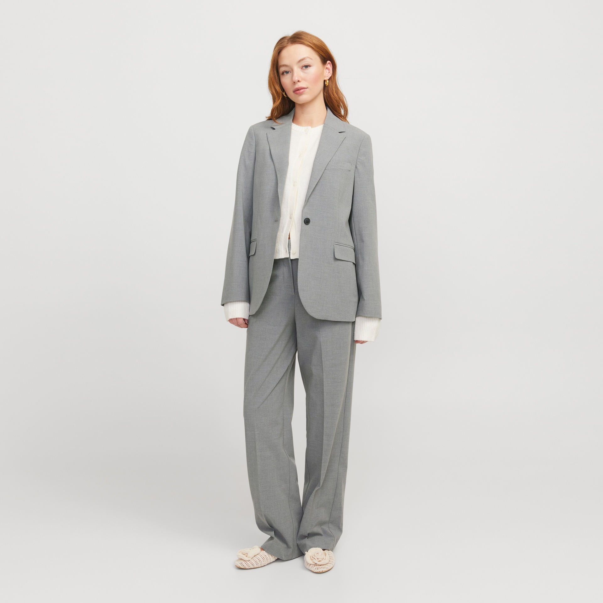 Conjunto cinzento de blazer e calças com camisola branca e sapatos bege de malha