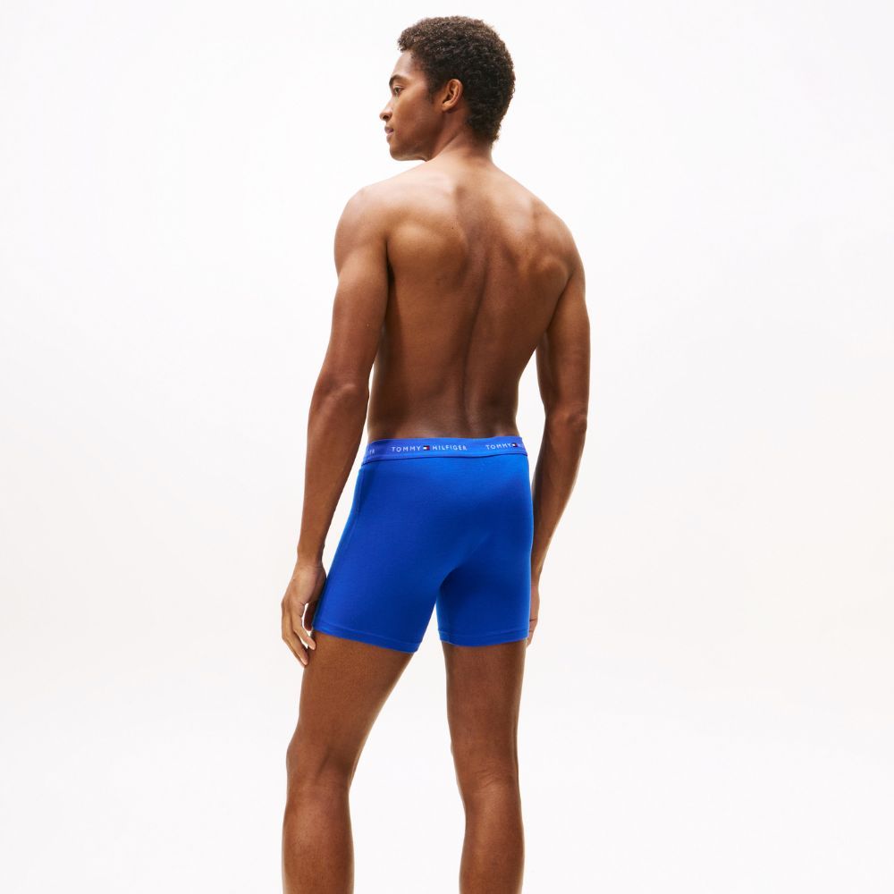 Homem de costas com boxers azuis Tommy Hilfiger num fundo branco.