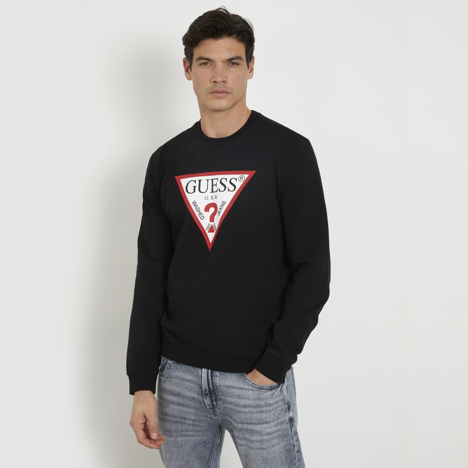 Homem vestido com sweatshirt preta GUESS e jeans azuis