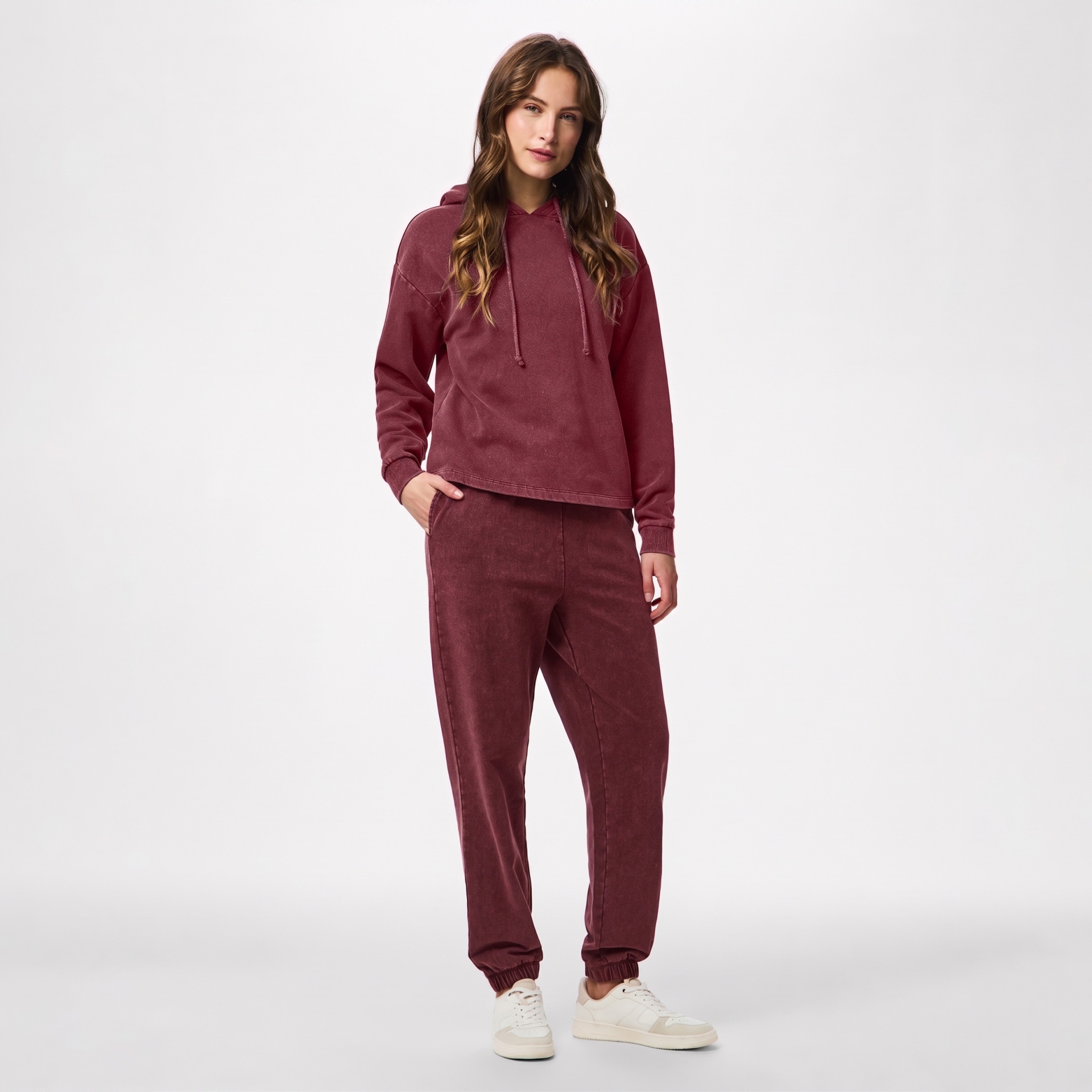 Mulher com conjunto bordô de hoodie e calças de felpa e ténis brancos