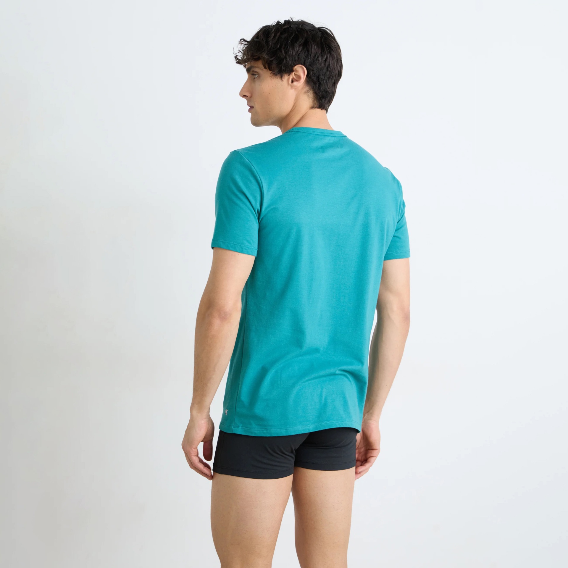 Homem de costas com t-shirt azul turquesa e calções pretos